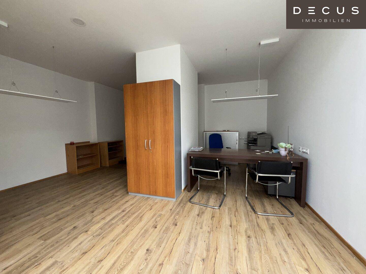 Modernes Büro mit Laminatboden, Schreibtischen und Stauraum in einem hellen Raum.