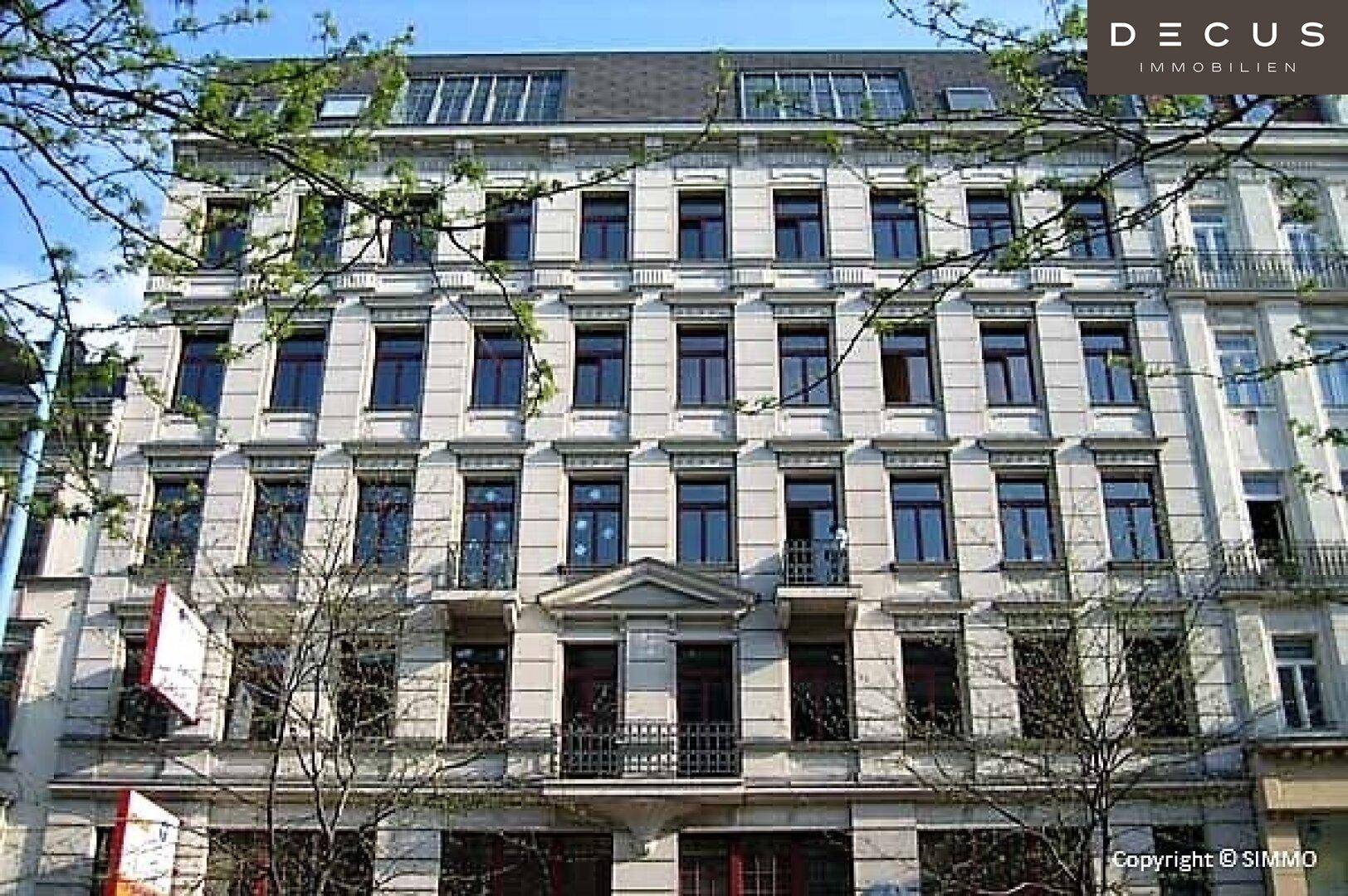 Historische Fassade eines Mehrfamilienhauses mit zahlreichen Fenstern und kleinen Balkonen.