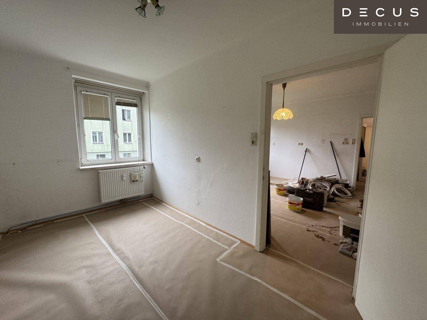 Renovierungsbedürftiges Zimmer mit Blick in einen weiteren Raum, viel Potenzial.