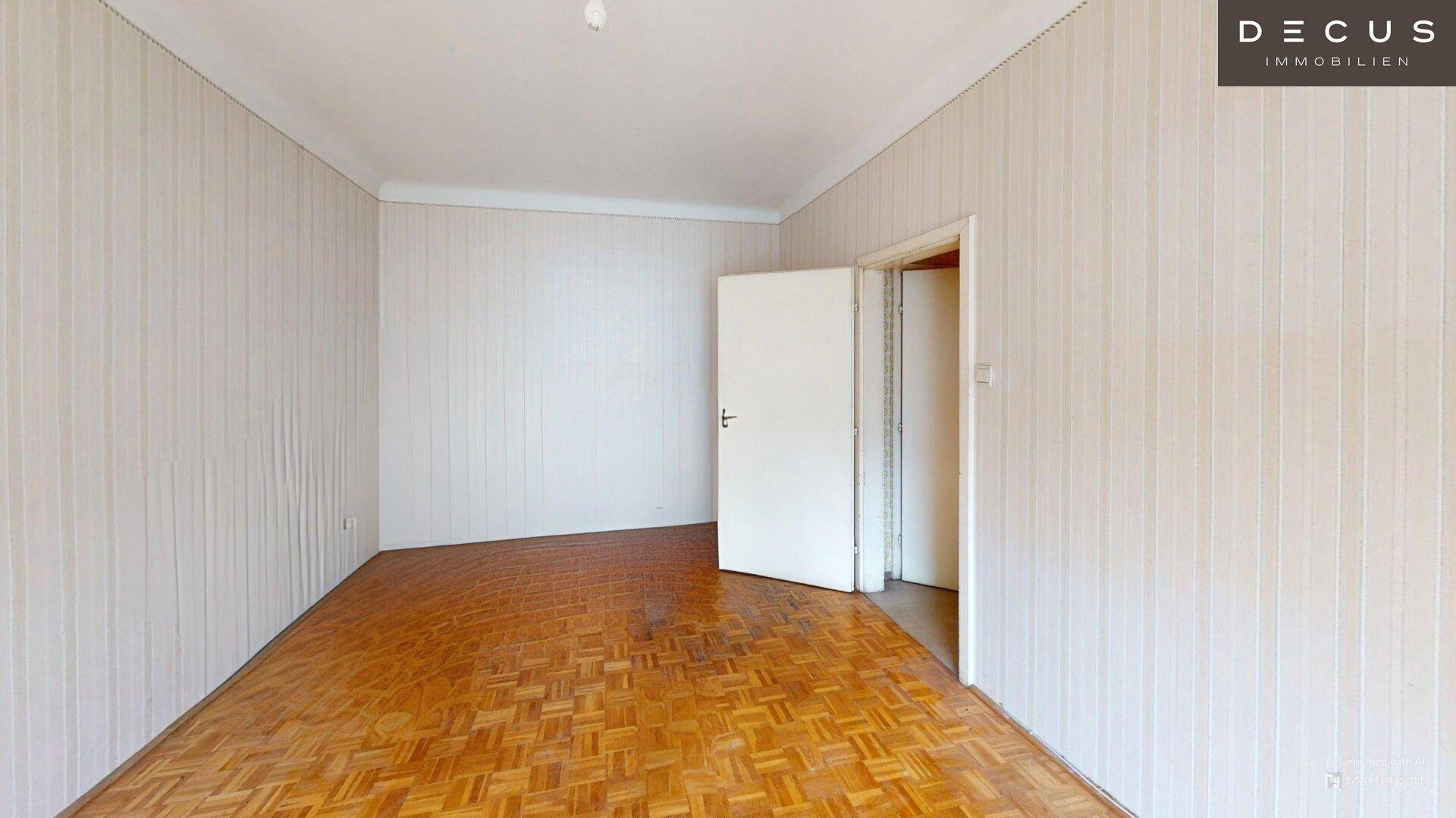 Geräumiger, leerer Wohnraum mit Fischgrätparkett und gestreiften Tapeten, ideal für eine Neugestaltung.