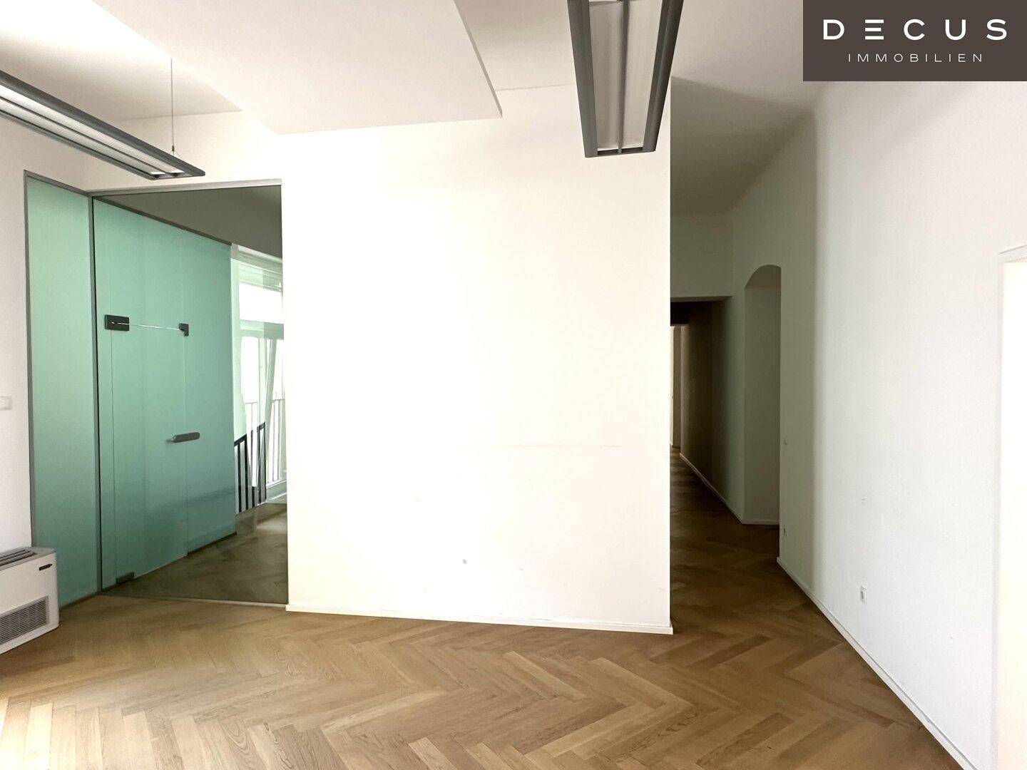 Offener Bürobereich mit Fischgrätparkett, Milchglastüren und einem langen Flur, modern und funktional.