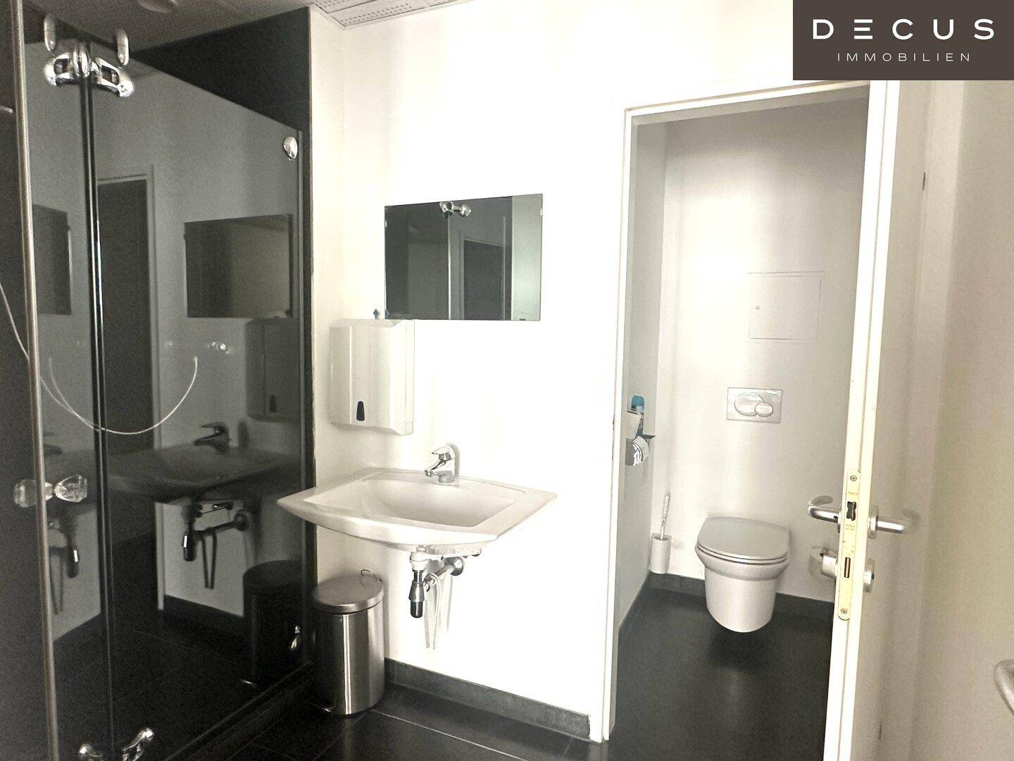 Modernes Badezimmer mit Waschbecken, Duschkabine und separatem WC-Bereich, funktional und sauber.