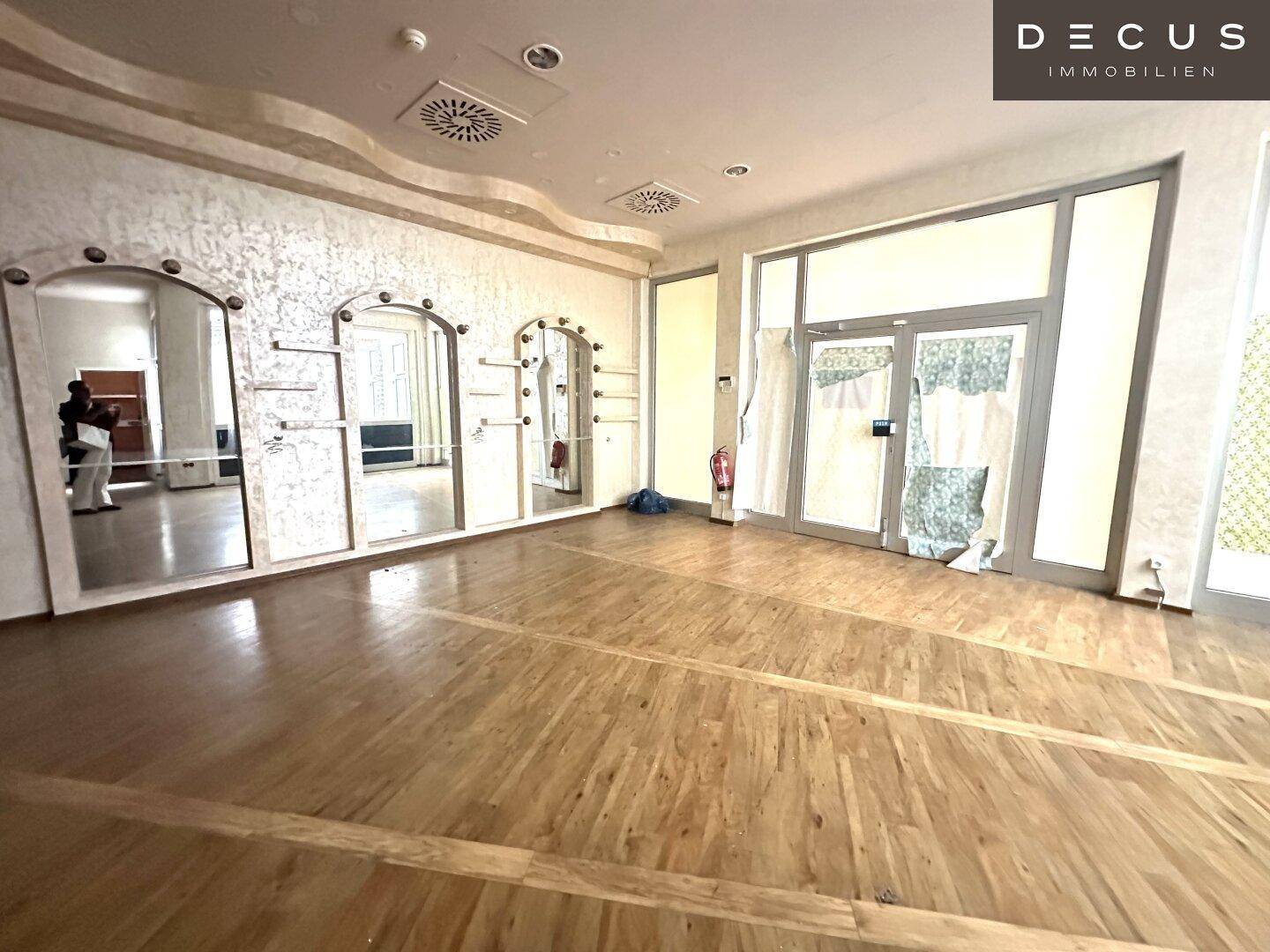 Großer Gewerberaum mit Holzboden, dekorativen Spiegelwänden und Regalen, ideal für Ladenflächen.