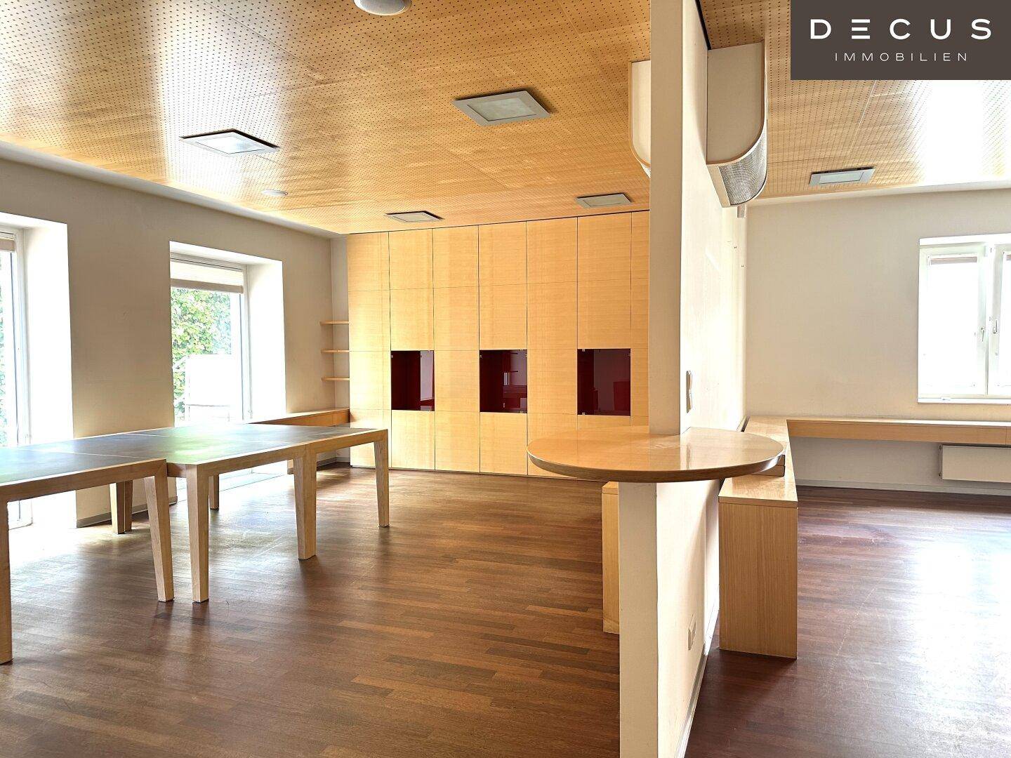 Heller Mehrzweckraum mit Holzboden, Holzdecke und integrierten Schränken, ideal für verschiedene Nutzungen.