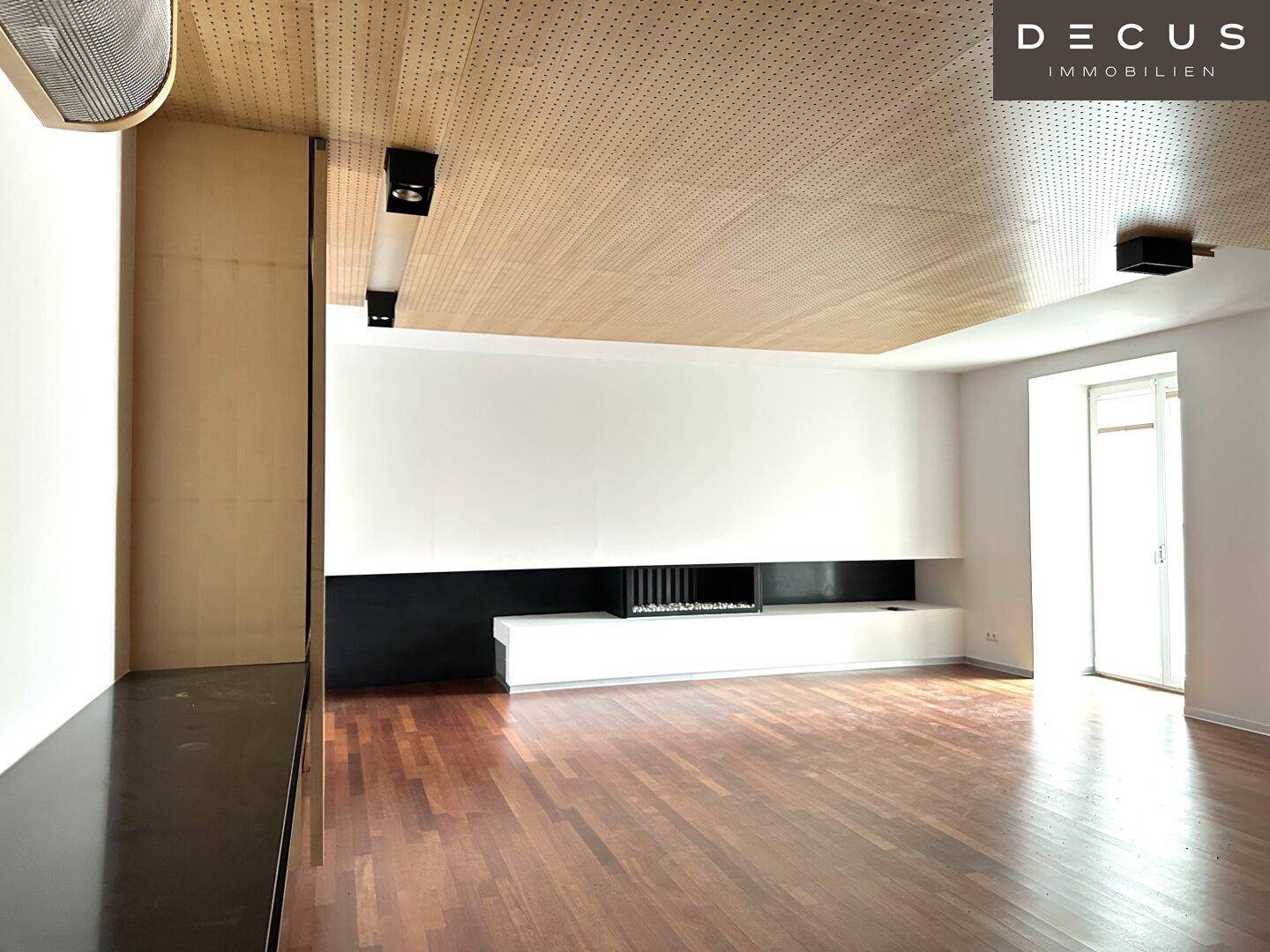 Geräumiges Wohnzimmer mit Holzboden, Holzlamellendecke und einem modernen, integrierten Kamin.