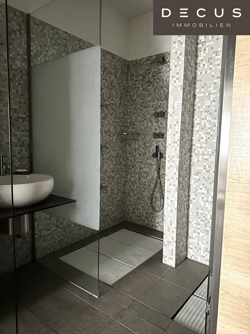 Modernes Badezimmer mit Mosaikfliesen, einer begehbaren Dusche und einem stilvollen Aufsatzwaschbecken.