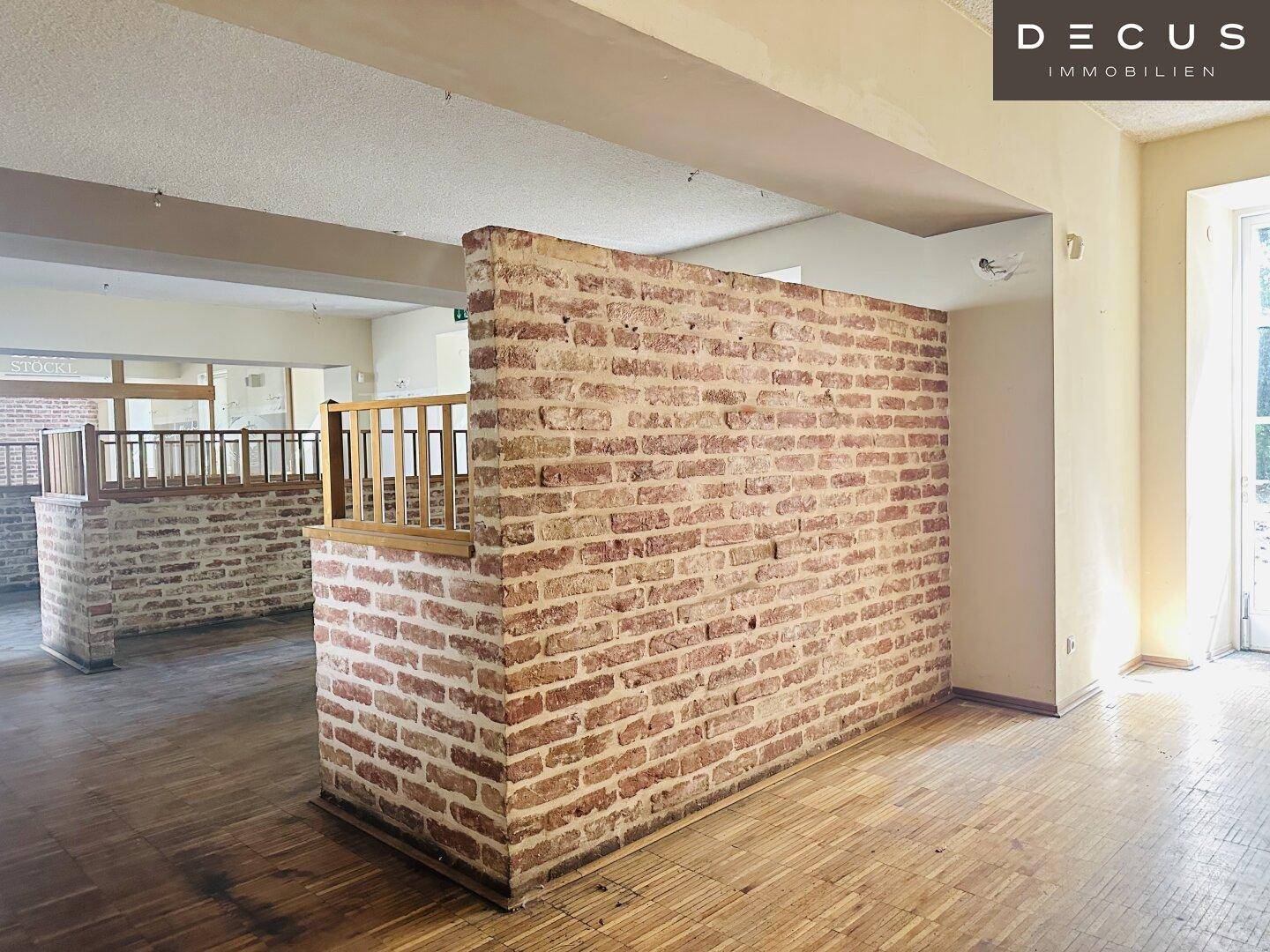Innenraum mit freigelegter Ziegelwand und Holzparkett, bietet viel Potenzial für Gestaltung.