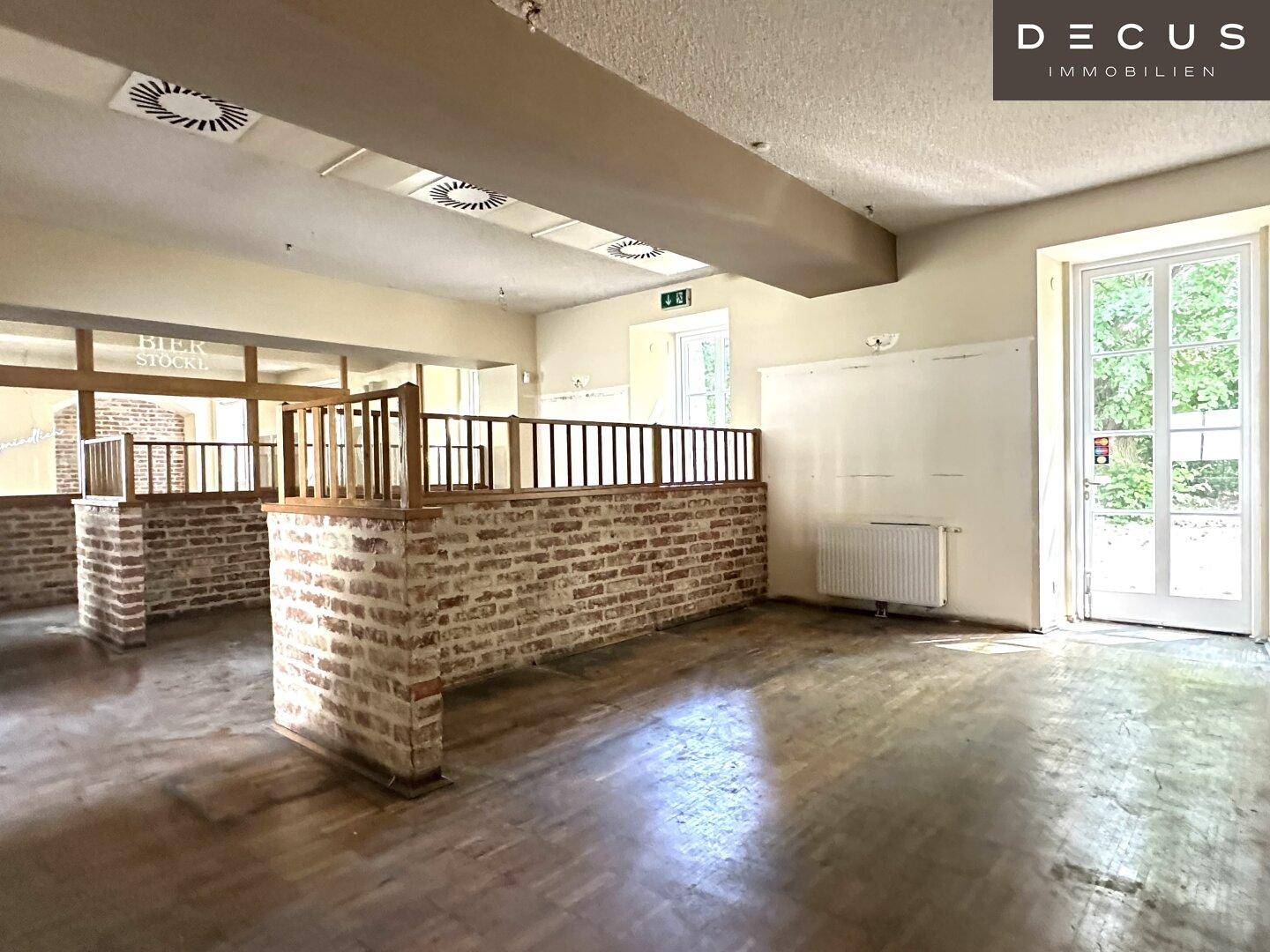 Geräumiger Innenbereich mit freigelegten Ziegelwänden und Holzparkett, bereit für eine neue Gestaltung.