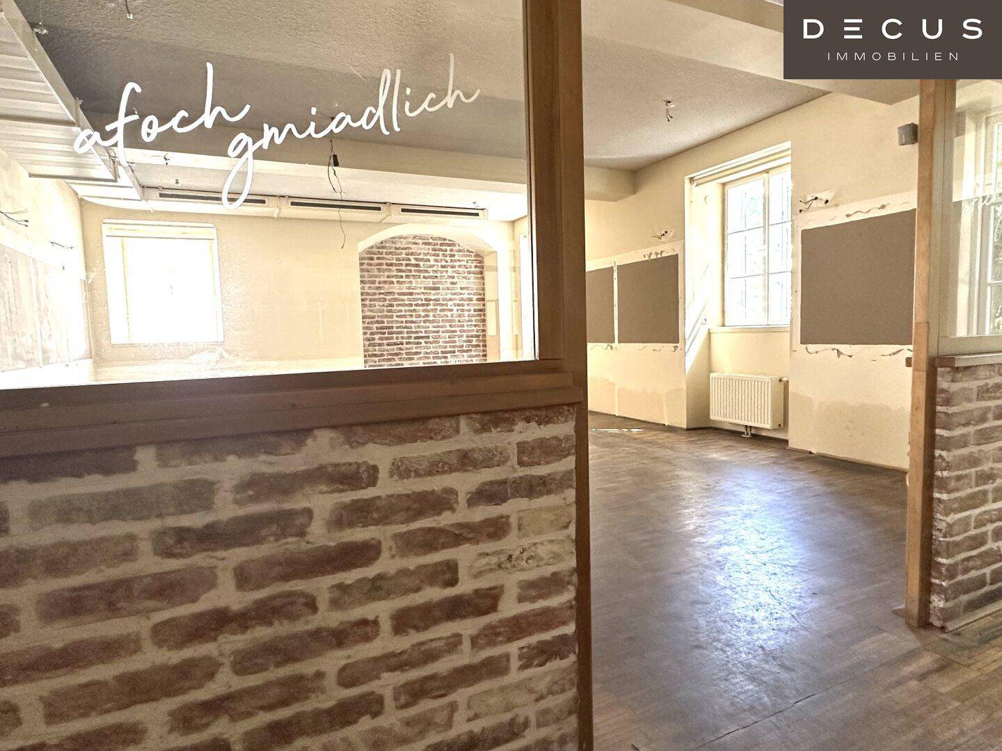 Heller Raum mit großen Fenstern, freigelegten Ziegelwänden und Holzparkett, ideal für ein Geschäft.