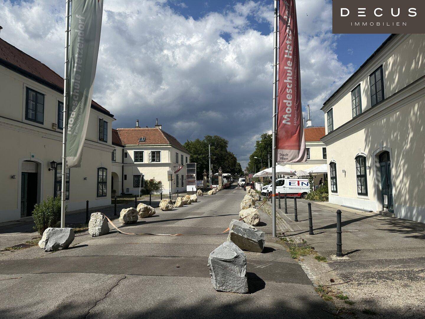 Straße mit historischen Gebäuden und Werbebannern unter einem bewölkten Himmel.