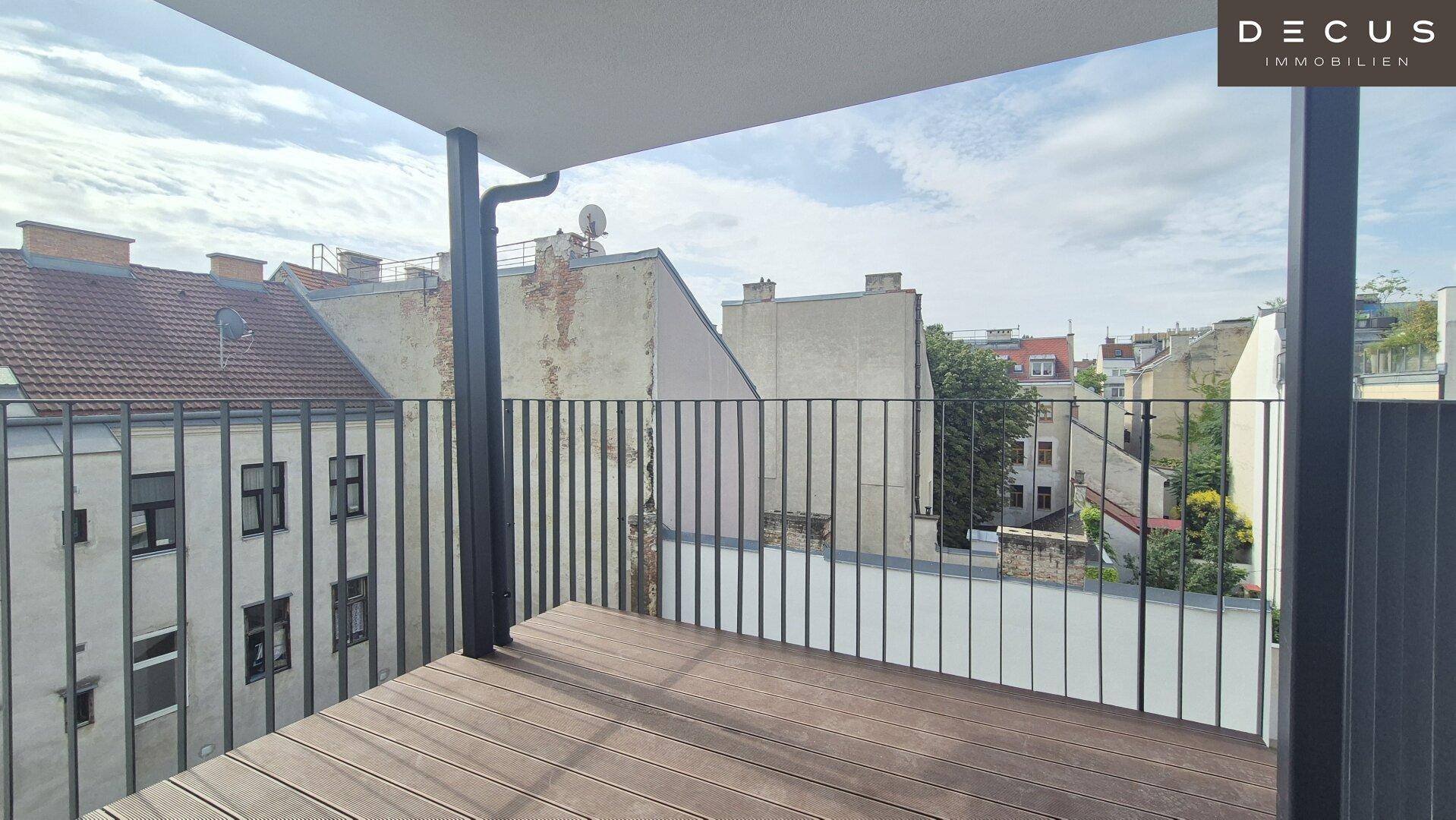 Moderner Balkon mit Holzboden und Blick über die Dächer der Stadt.