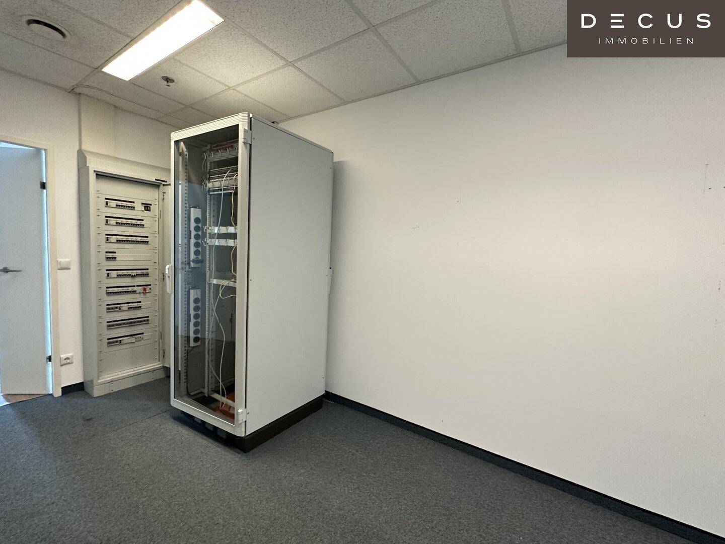 Technikraum mit einem Serverschrank und geöffneten Elektroschränken, bereit für die Installation.