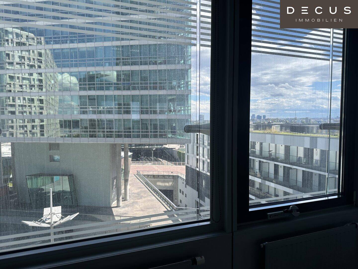 Fensterblick aus einem Büro auf moderne Hochhäuser und die umliegende Stadtlandschaft.