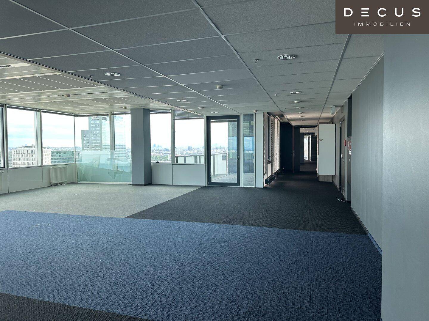 Geräumiges Büro mit großen Fenstern, Teppichboden und weitem Blick auf die Stadtlandschaft.