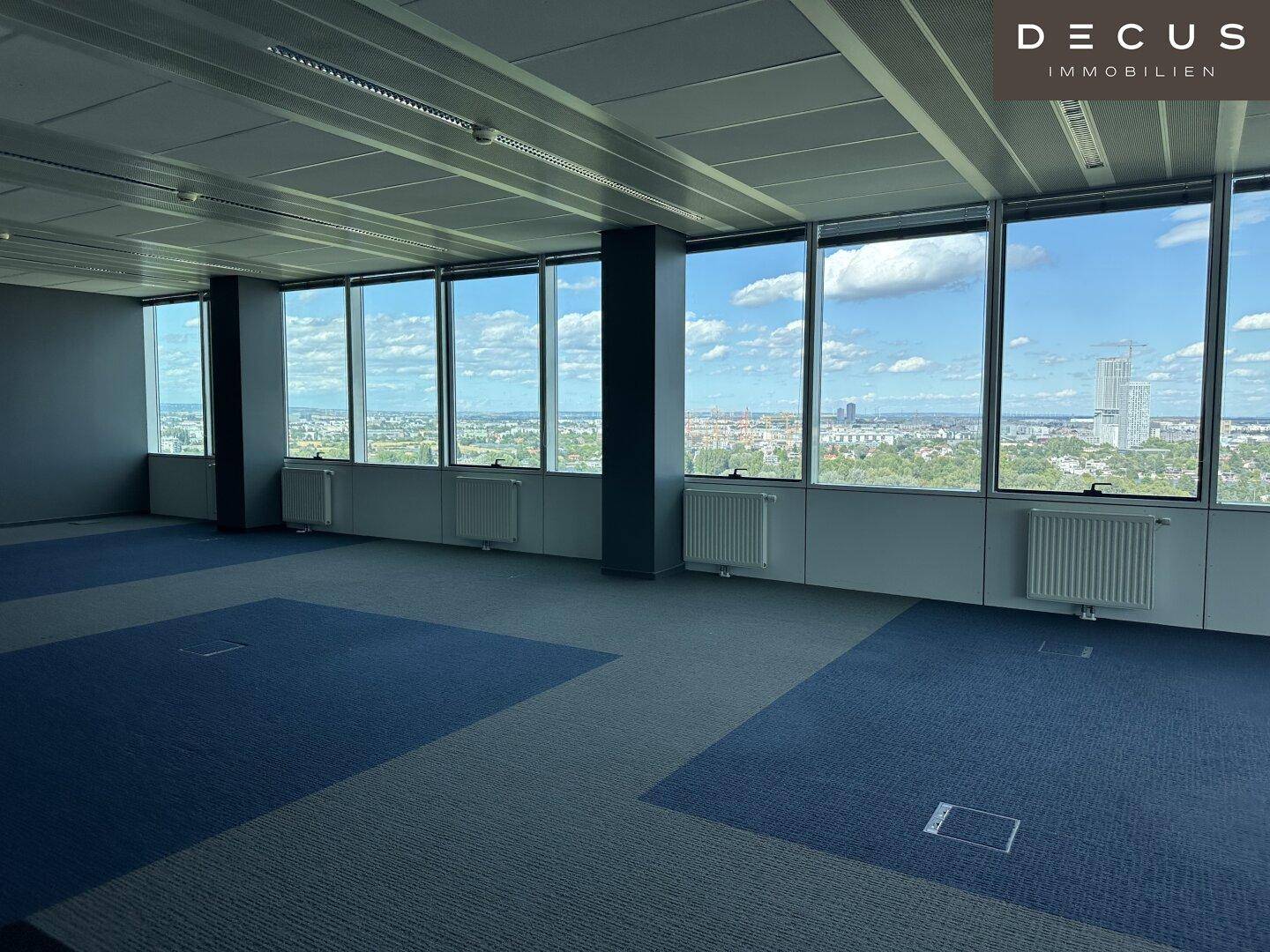 Heller Büroraum mit großen Fenstern, die einen weiten Blick auf die Stadt bieten.