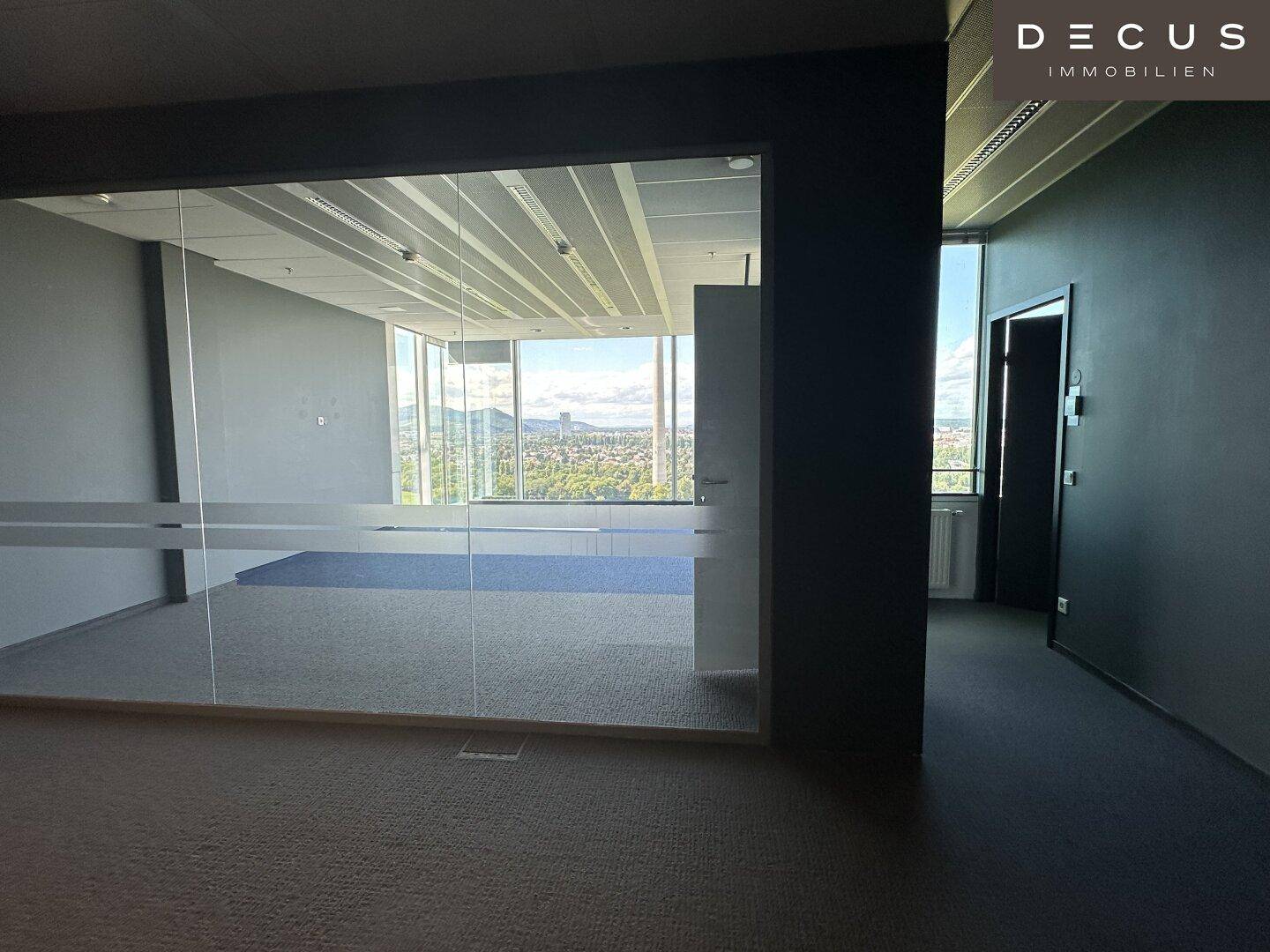 Büro mit Glaswänden und Teppichboden, bietet einen weiten Blick auf die Stadt und die umliegende Landschaft.