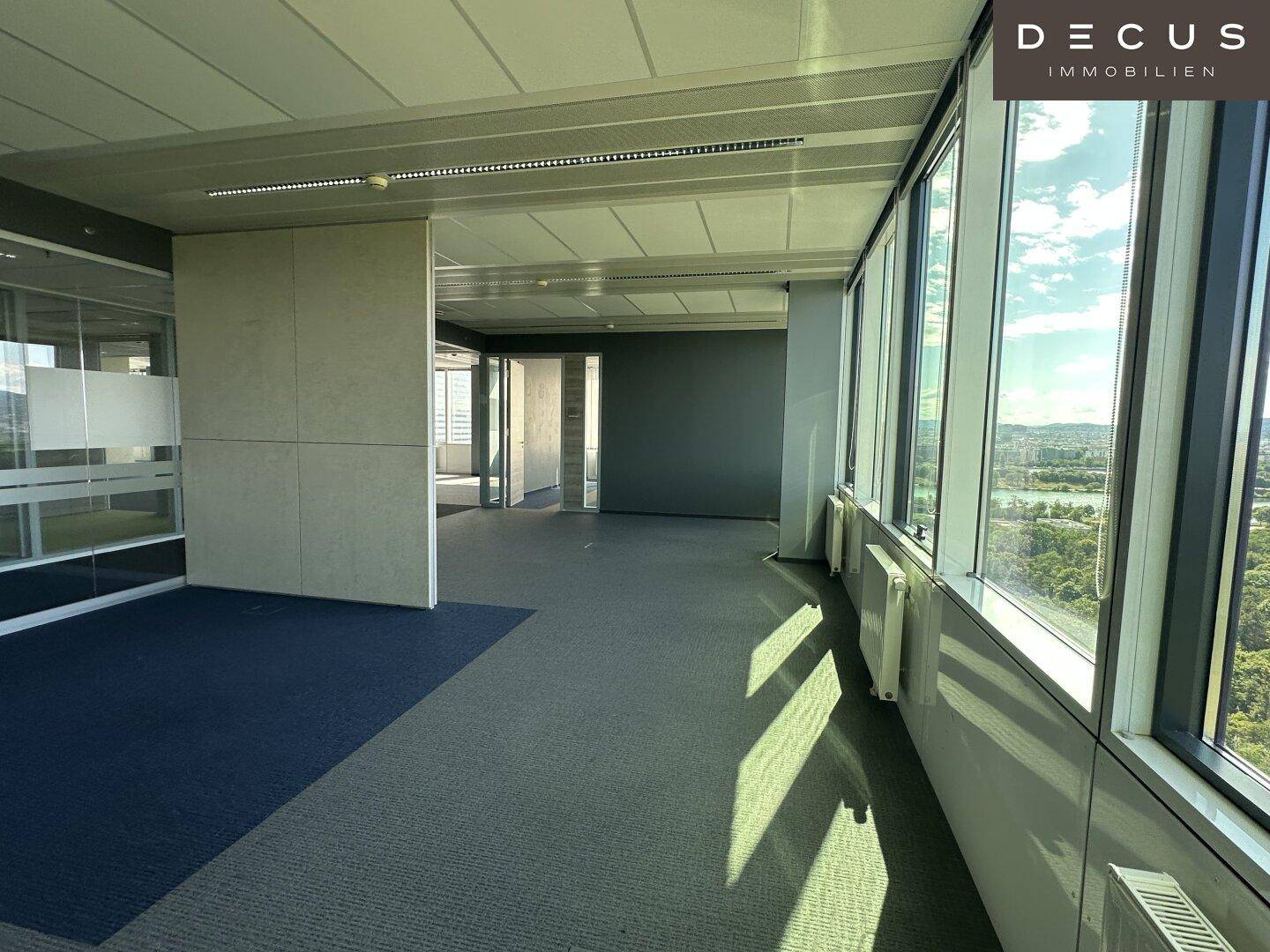 Flexibler Bürobereich mit Teppichboden und großen Fenstern, die viel Tageslicht hereinlassen.