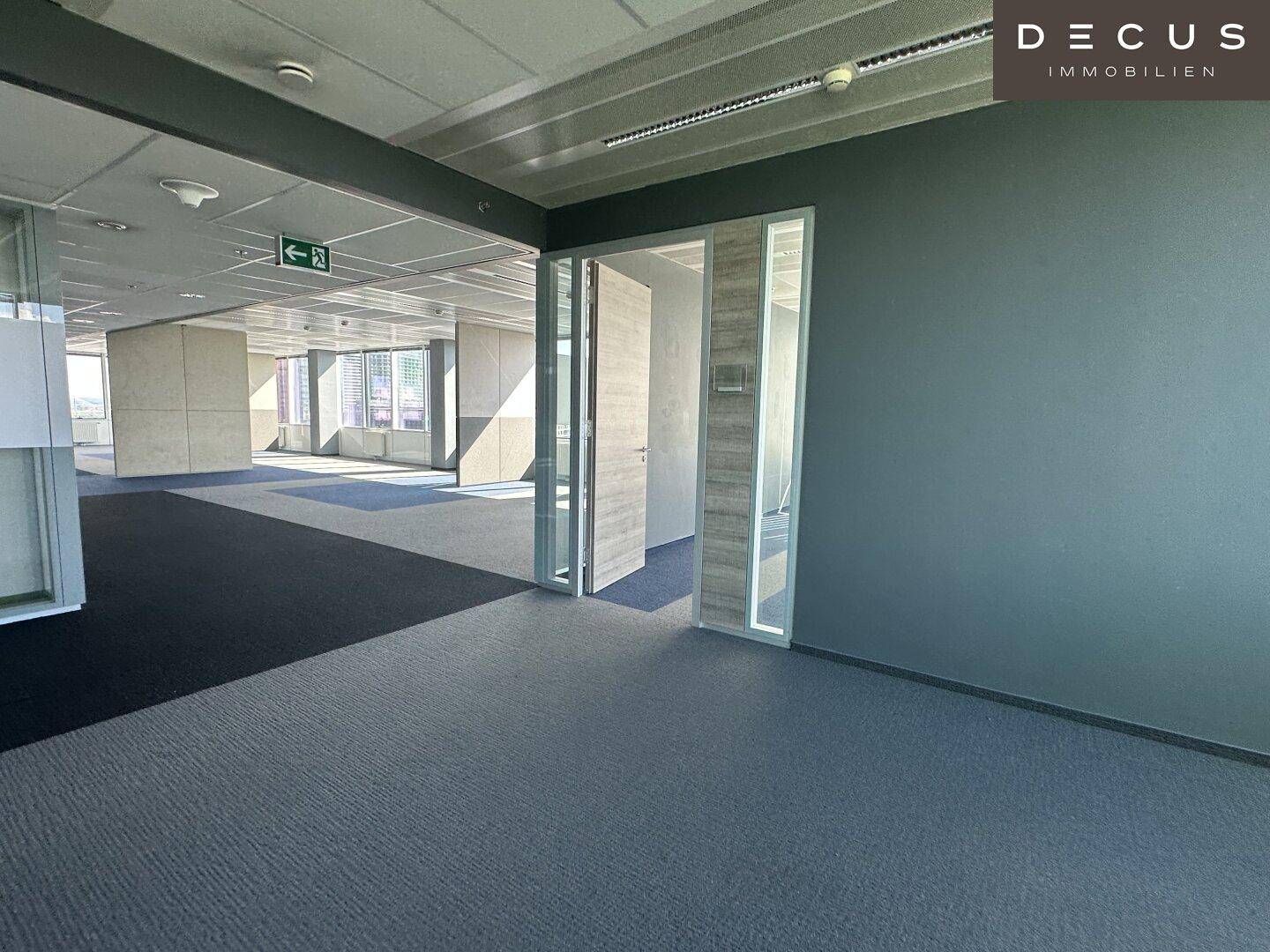 Moderner Bürogang mit Teppichboden und Glastüren, der zu weiteren Büroräumen führt.