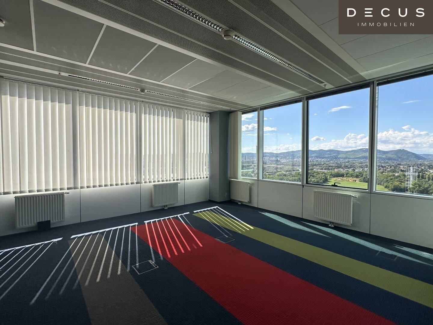 Büro mit vertikalen Jalousien an den großen Fenstern, die einen weiten Blick auf die Landschaft bieten.
