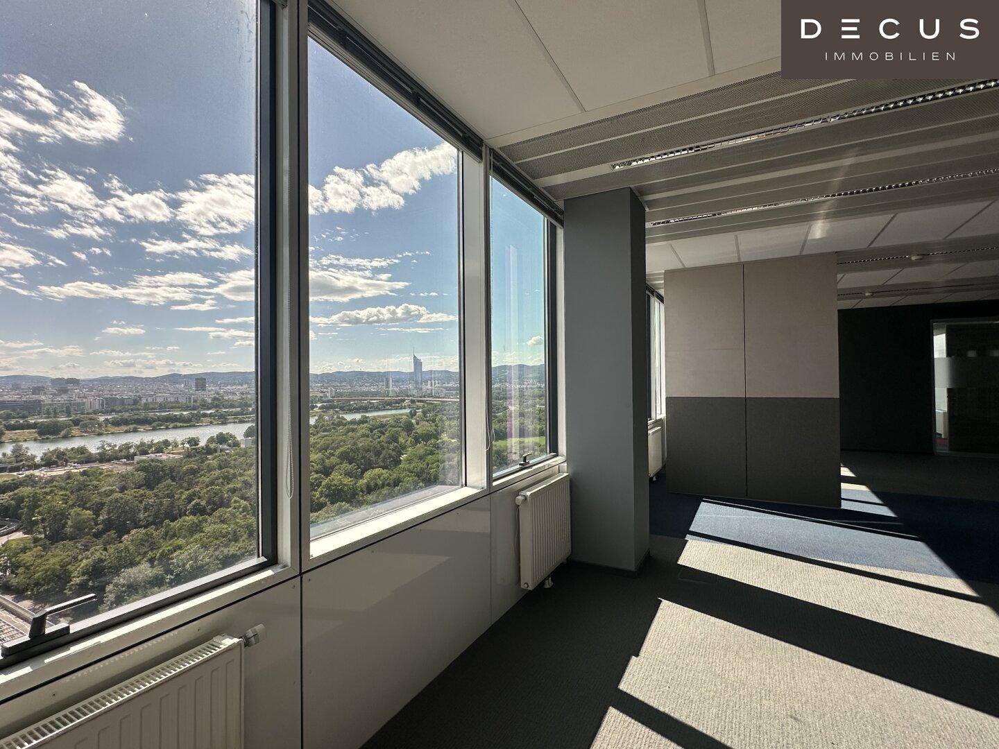Heller Büroraum mit Panoramablick auf die Stadt und den Fluss, durch raumhohe Fenster sichtbar.