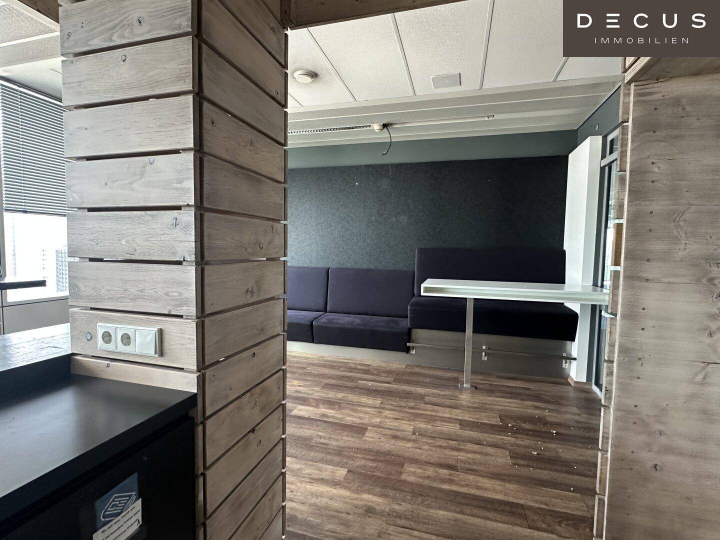 Gemütlicher Loungebereich mit dunklen Sofas und Holzelementen, ideal für entspannte Pausen.