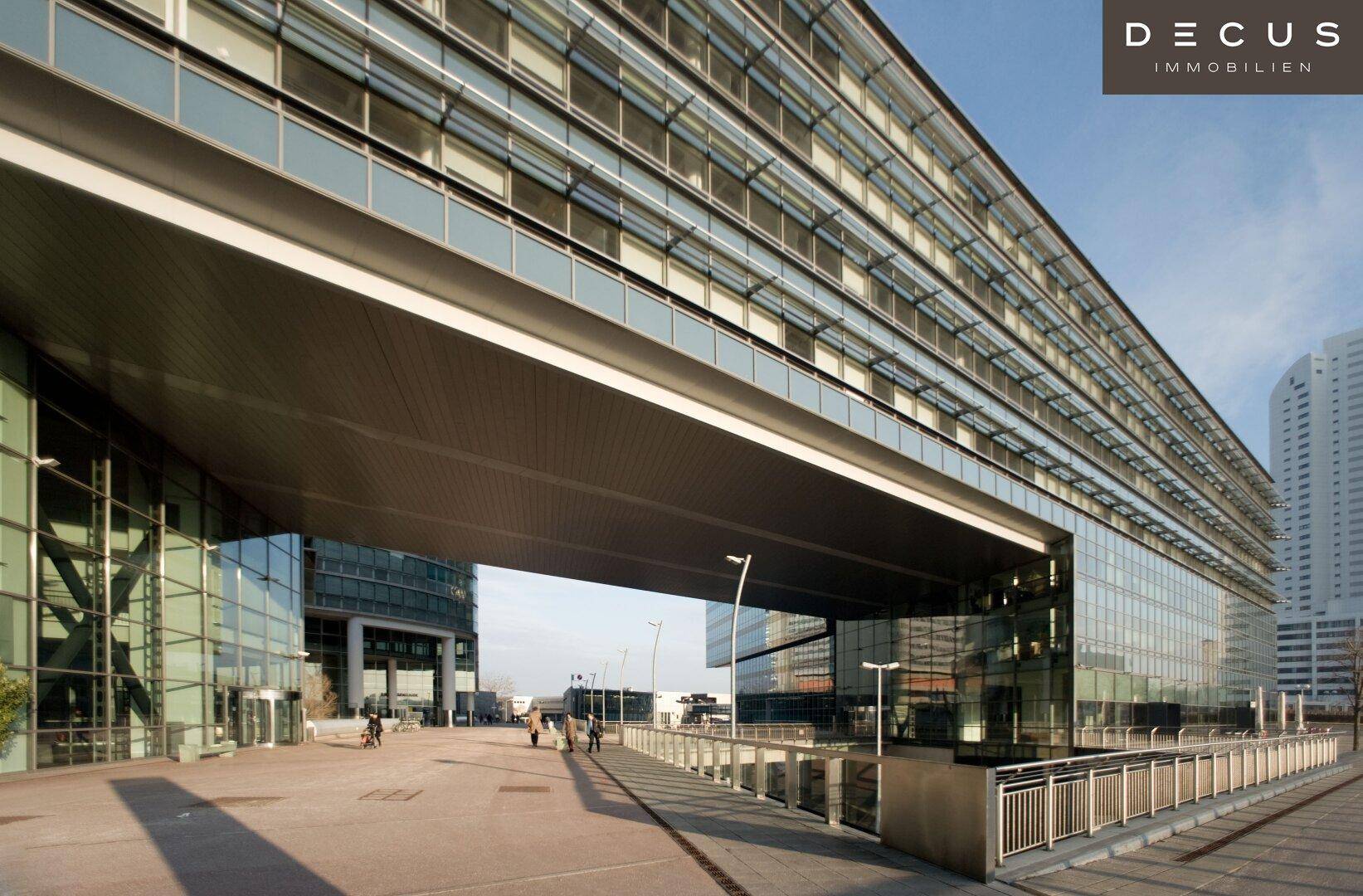 Blick auf die beeindruckende moderne Architektur des Gebäudes mit seiner weitläufigen Glasfront und der Überführung.