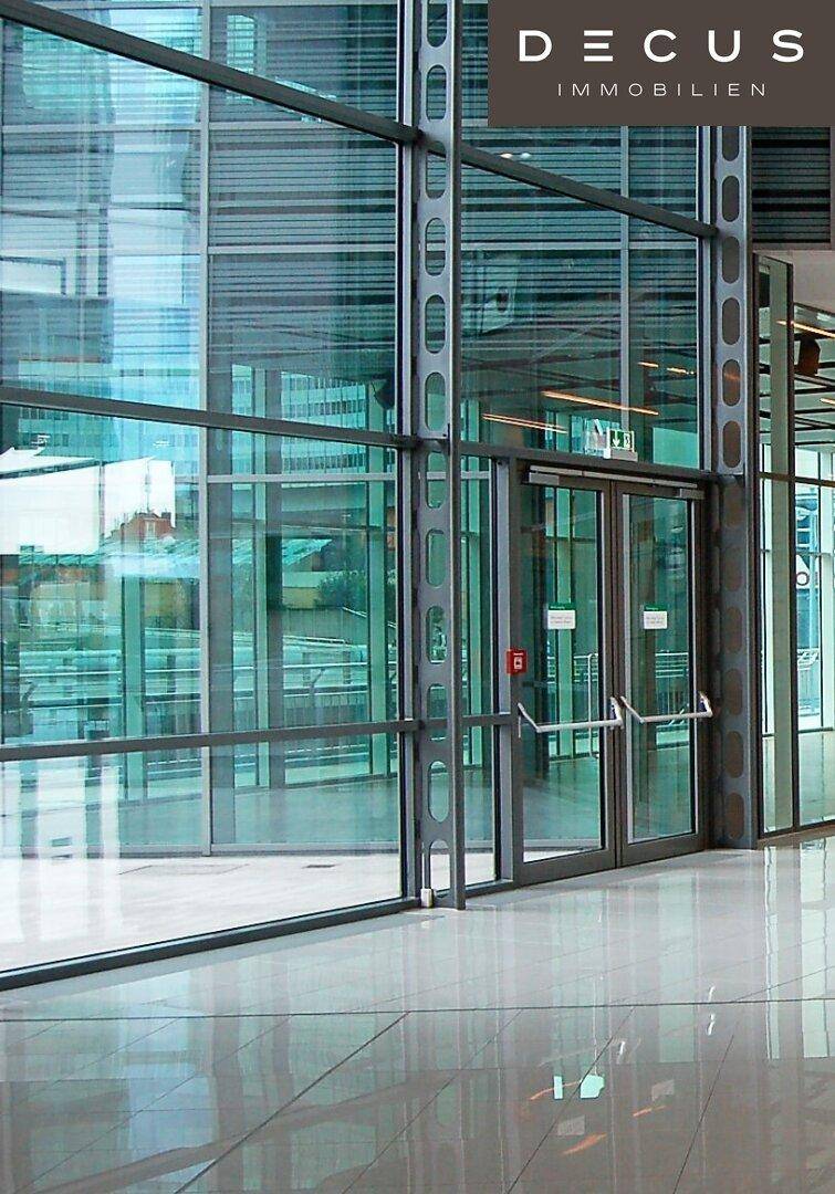 Helle und moderne Lobby mit großen Glasfronten, poliertem Boden und klaren Linien.