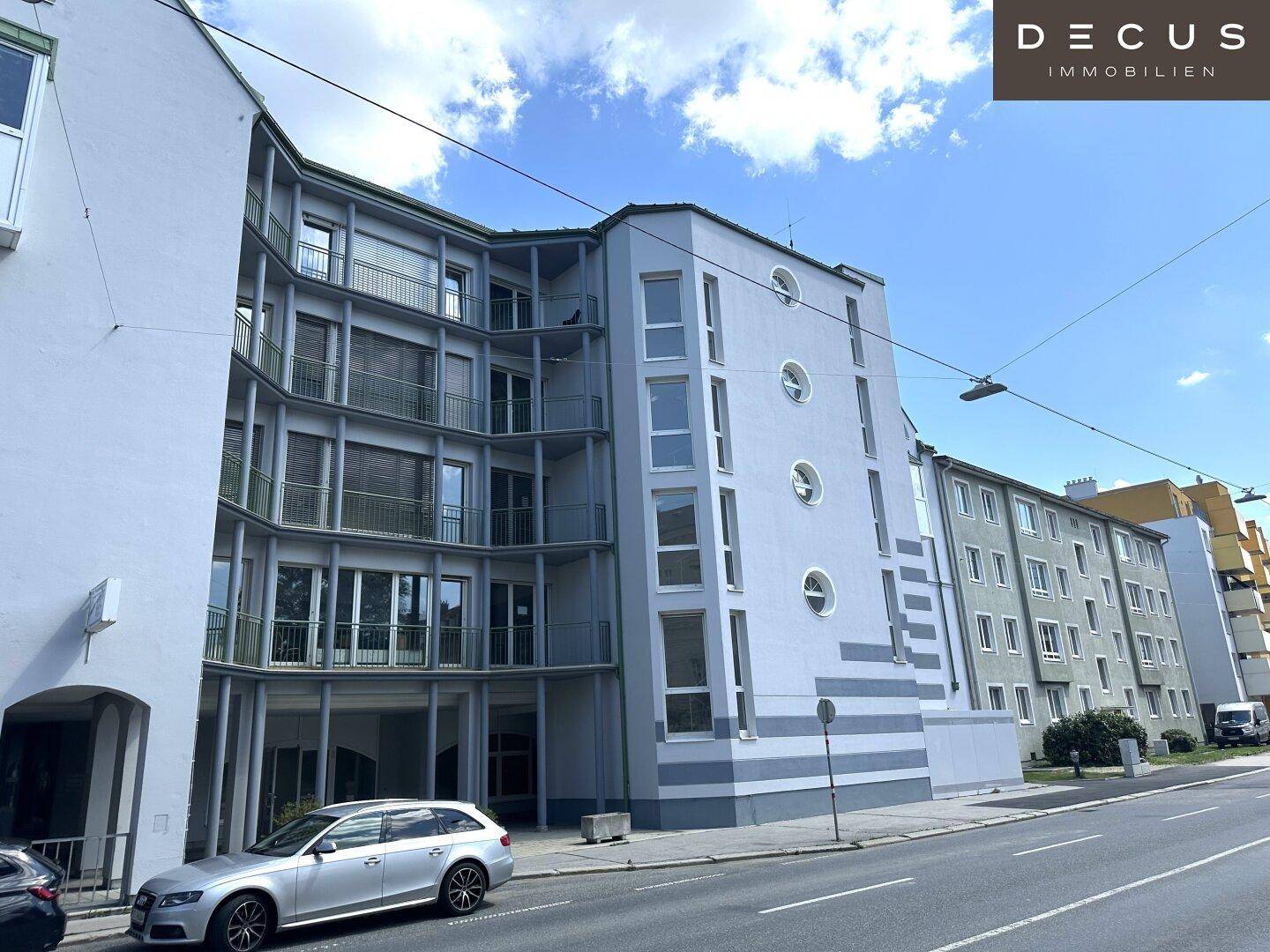 Ansicht eines modernen Gebäudes von der Straßenseite mit Balkonen und vielen Fenstern.