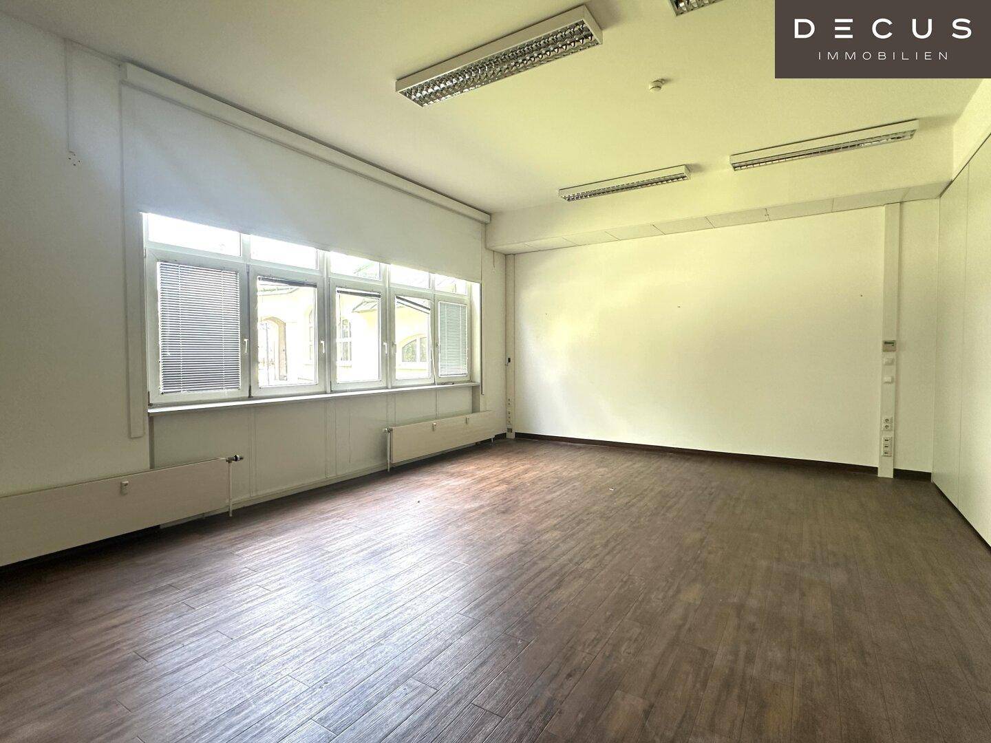 Geräumiger Büroraum mit großen Fenstern, die viel Tageslicht hereinlassen und eine helle Atmosphäre schaffen.