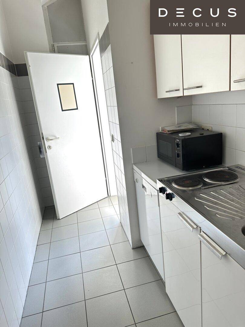Kleine Küchenzeile mit Spüle, Kochplatten und Mikrowelle, ideal für die Zubereitung einfacher Mahlzeiten.