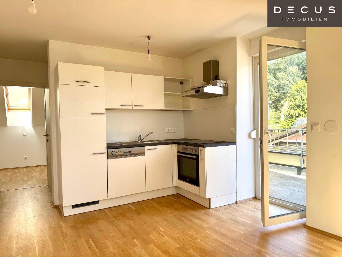Helle, moderne Einbauküche mit weißen Fronten, Parkettboden und direktem Zugang zum Außenbereich.