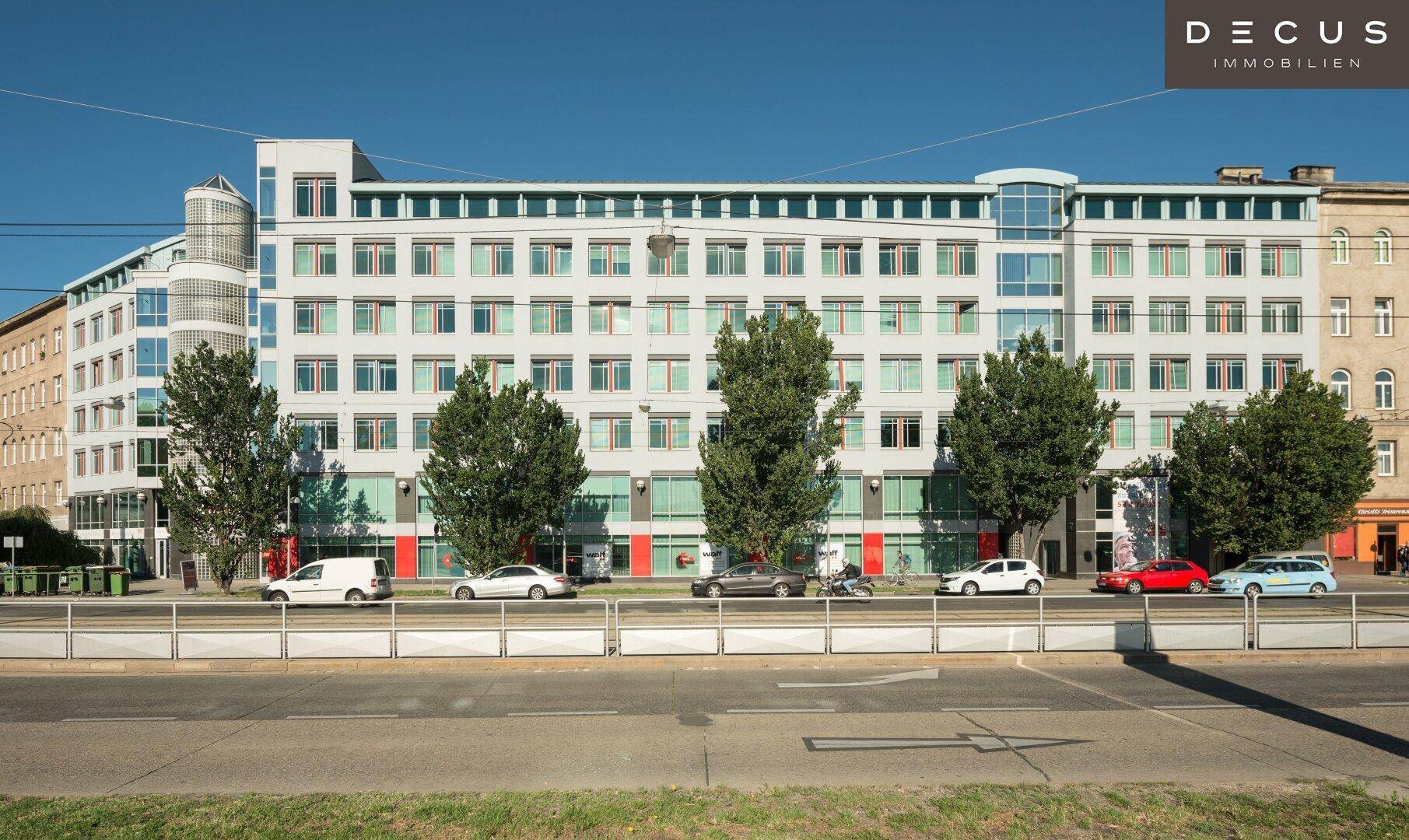 Gesamtansicht eines modernen Bürogebäudes mit vielen Fenstern und Bäumen davor.