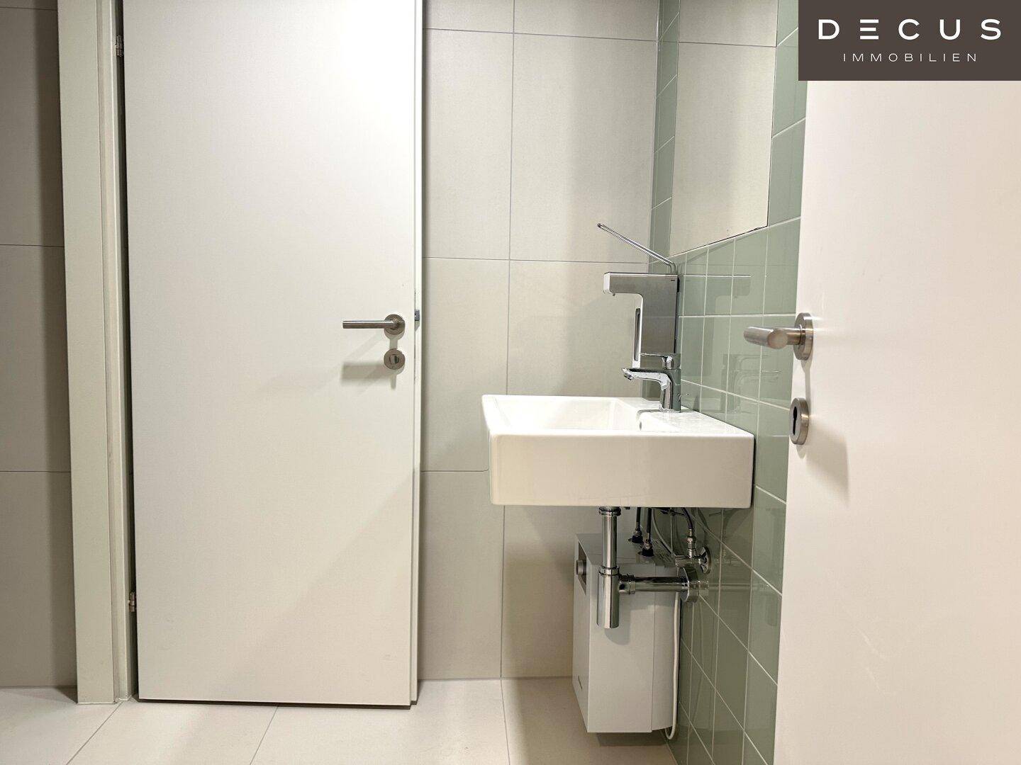 Modernes Badezimmer mit Waschbecken, Spiegel und hellen Fliesen, sauber und funktional.