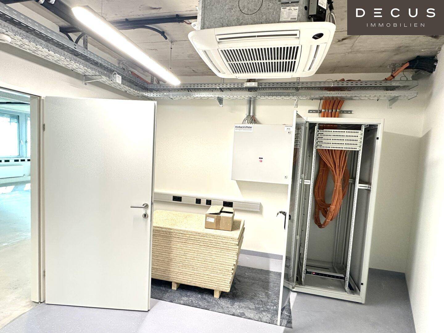 Technikraum mit Klimaanlage, Kabelkanälen und einem Serverschrank, bereit für den Betrieb.