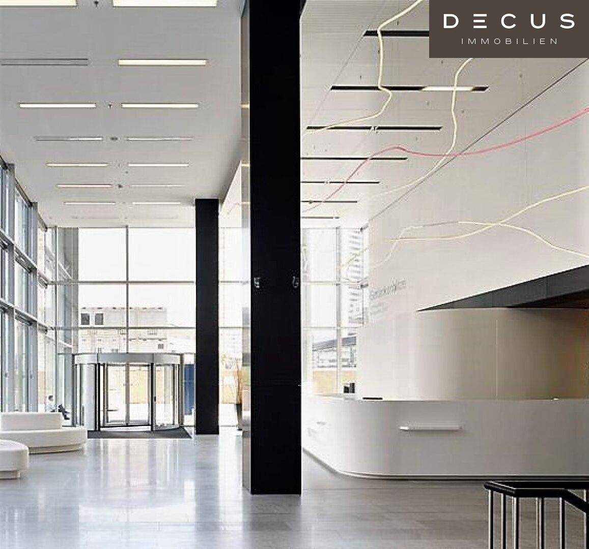 Geräumige und moderne Empfangshalle mit einer eleganten Rezeption, hohen Decken und viel Tageslicht.