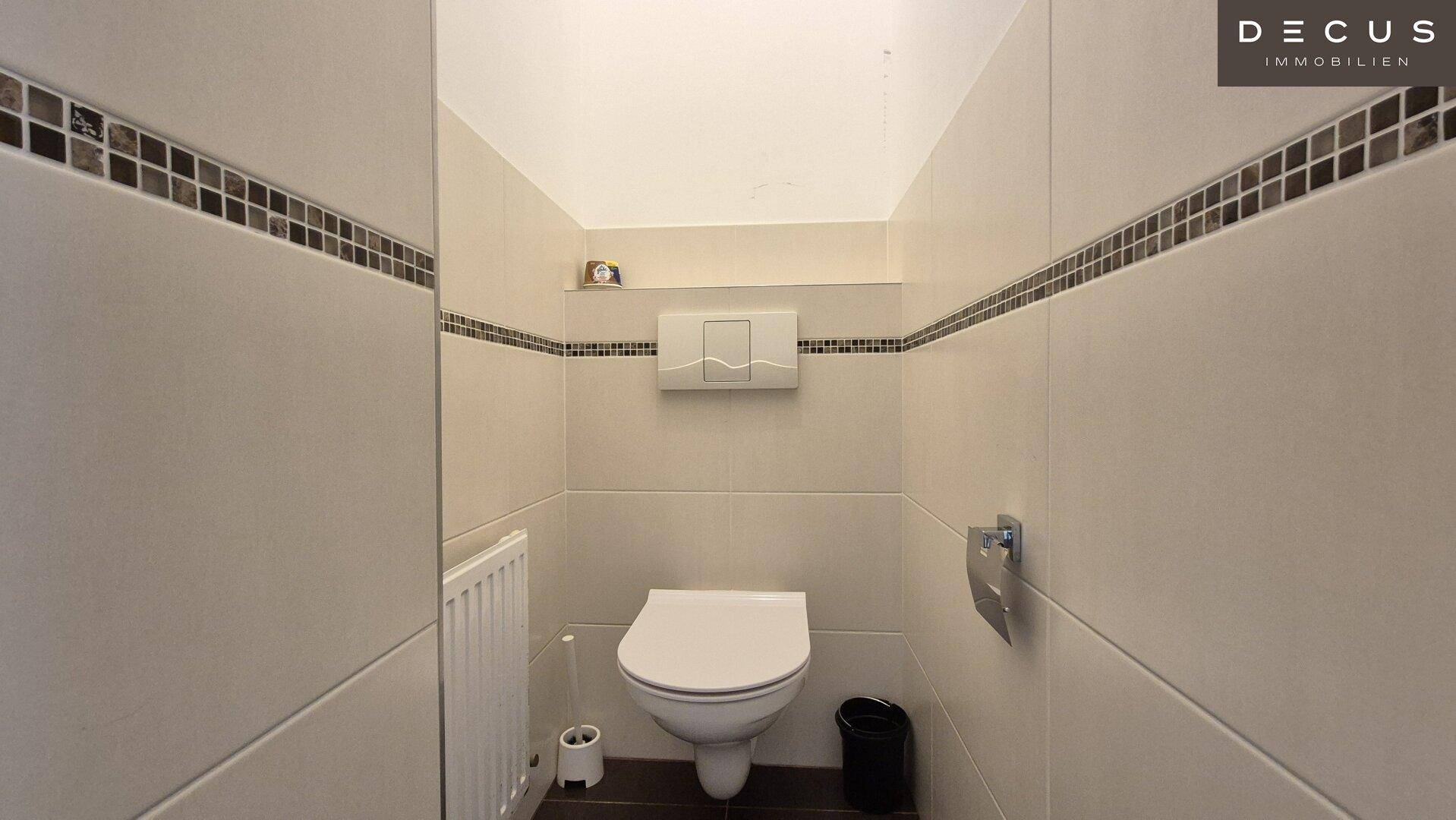 Separates WC mit wandhängender Toilette, Heizkörper und Fliesen an den Wänden.