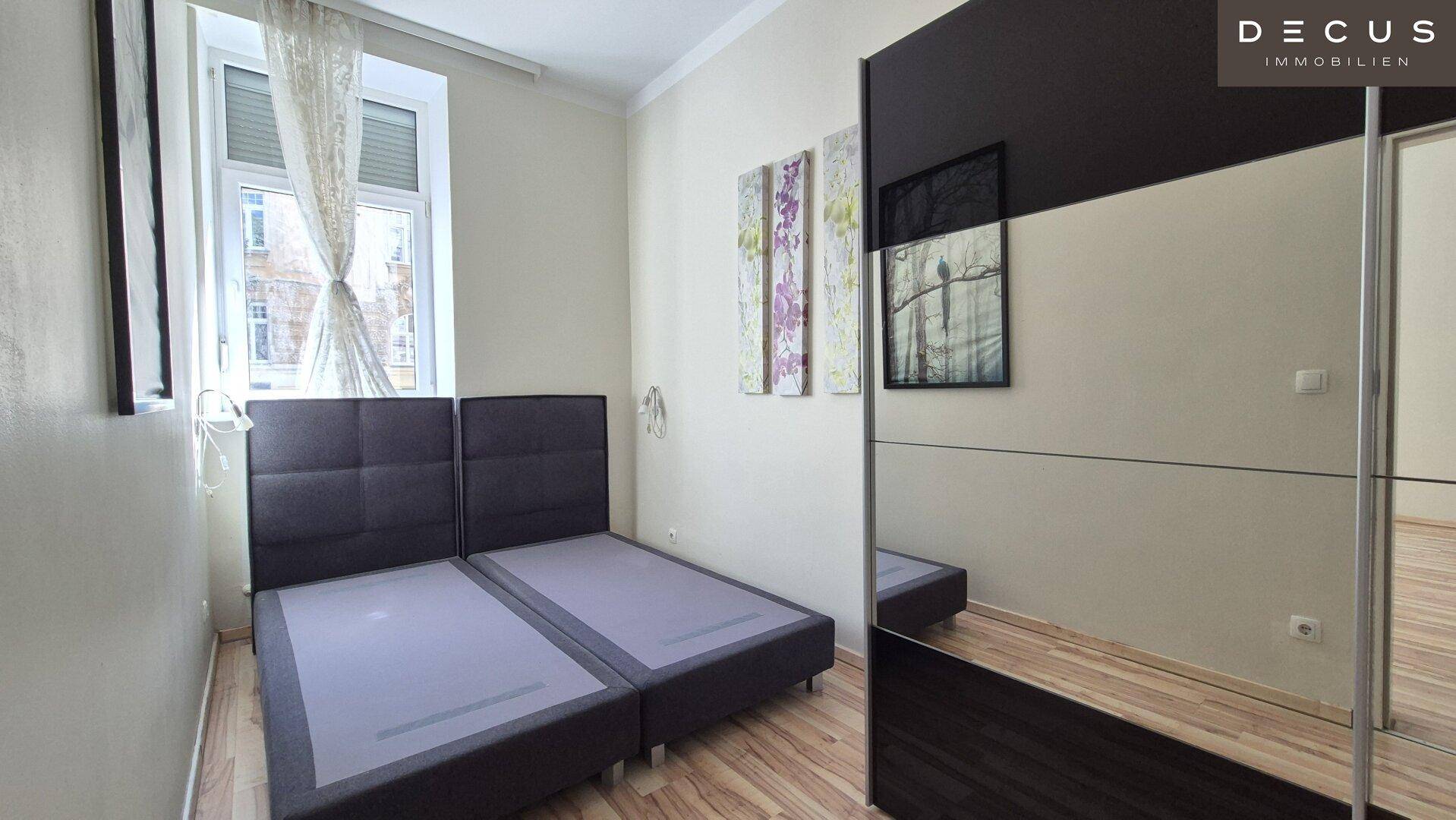 Schlafzimmer mit Holzboden, Doppelbett und großem Spiegelschrank.