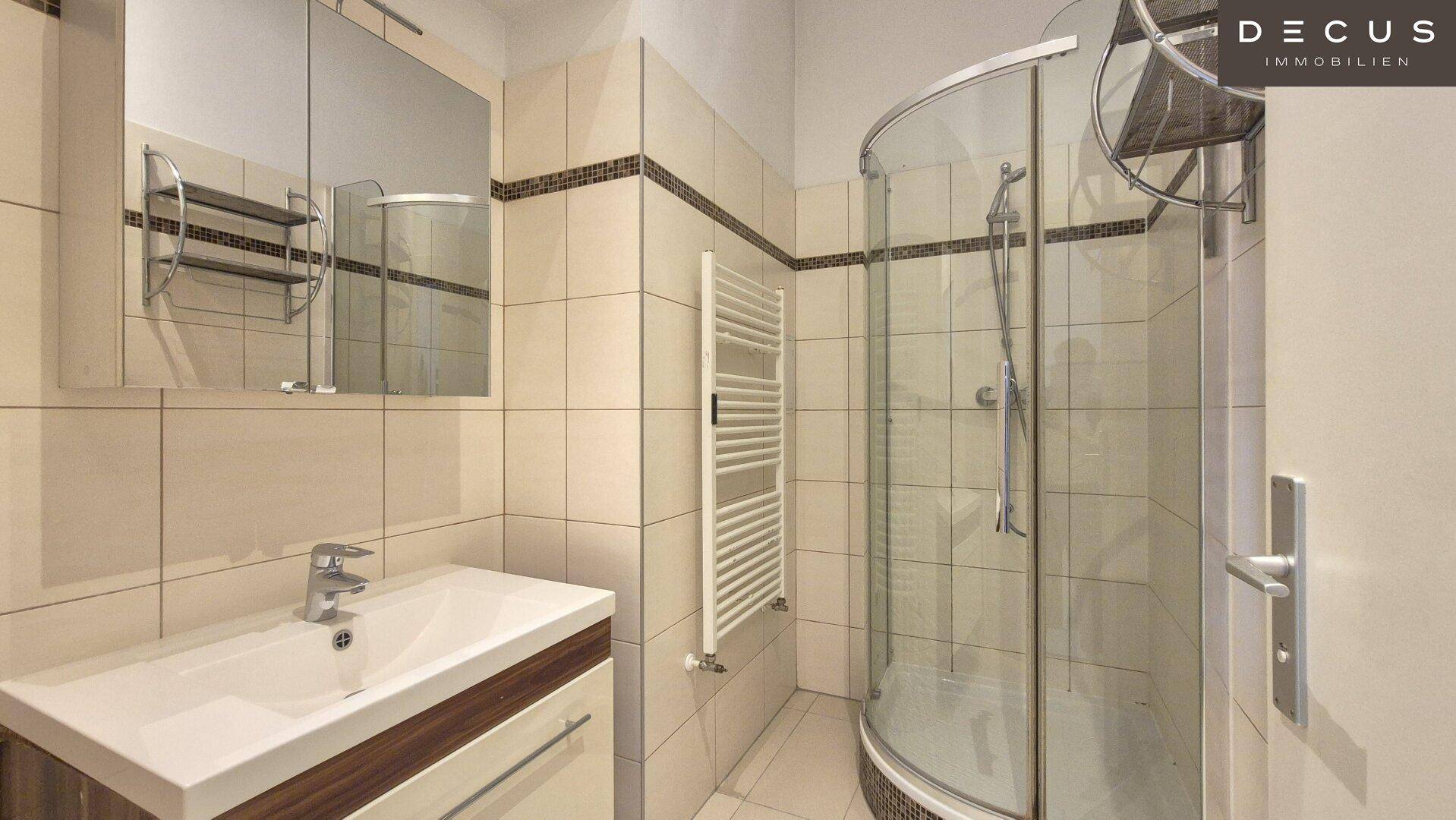 Modernes Badezimmer mit Duschkabine, Waschbecken und beheiztem Handtuchhalter.