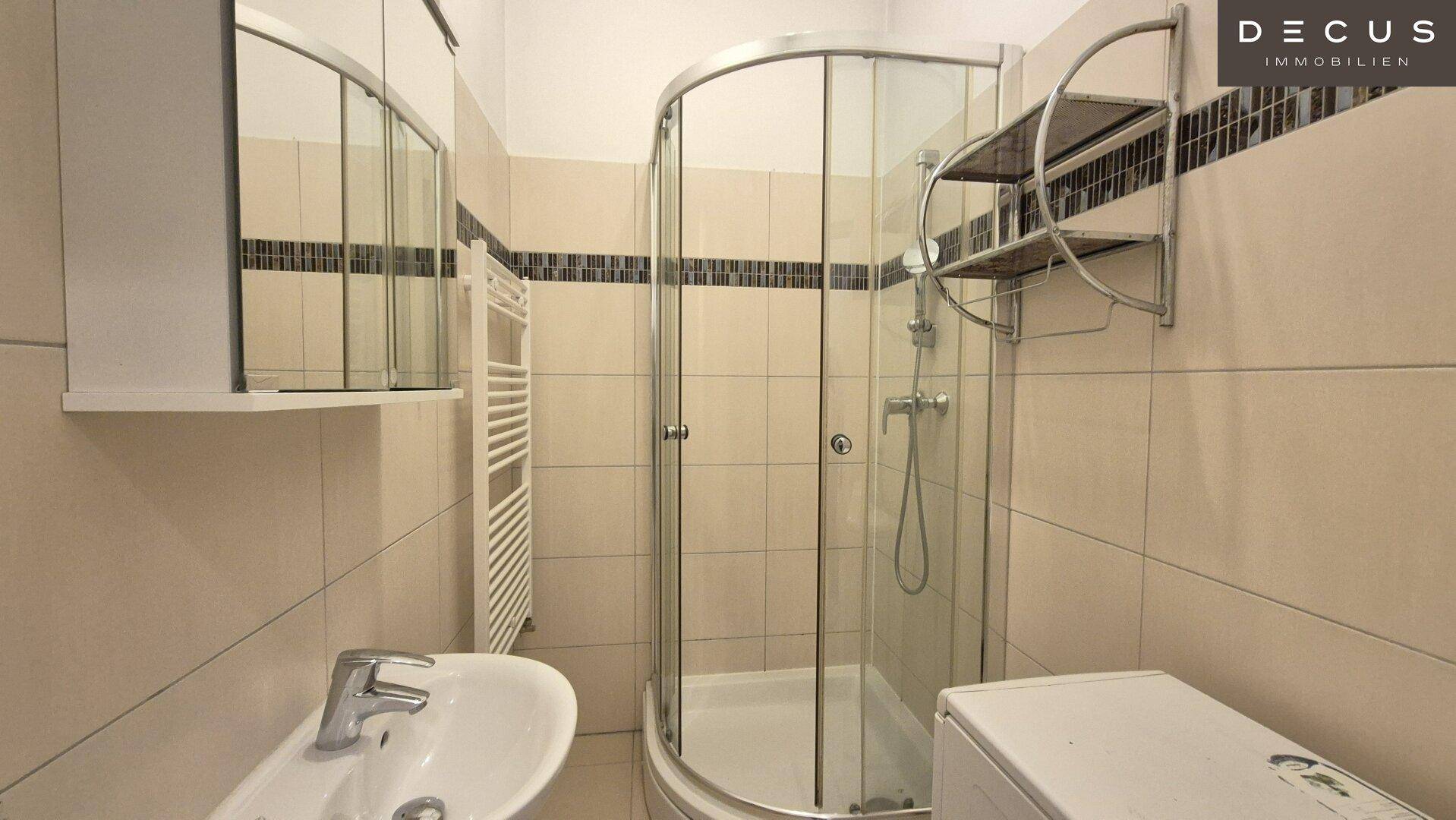 Modernes Badezimmer mit Duschkabine, Waschbecken und Fliesen an Wänden und Boden, inklusive Handtuchheizkörper.
