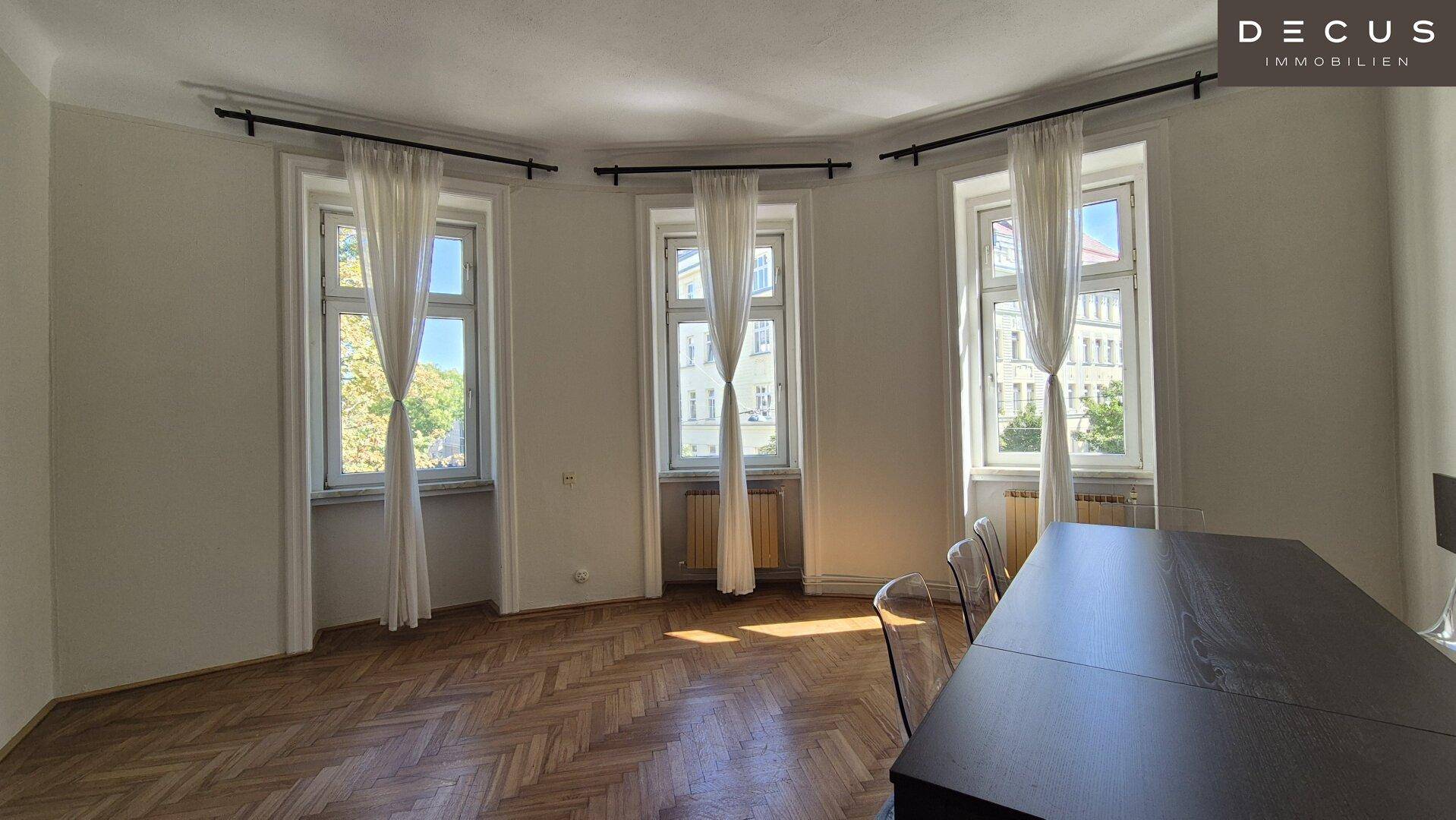 Geräumiger Wohn-Essbereich mit Fischgrätparkett und einem Esstisch, ideal für gesellige Runden.