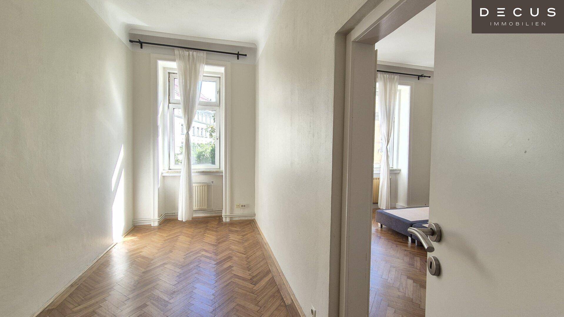 Leeres Zimmer mit Fischgrätparkett und Zugang zu einem weiteren Raum, ideal als Schlafzimmer oder Büro.