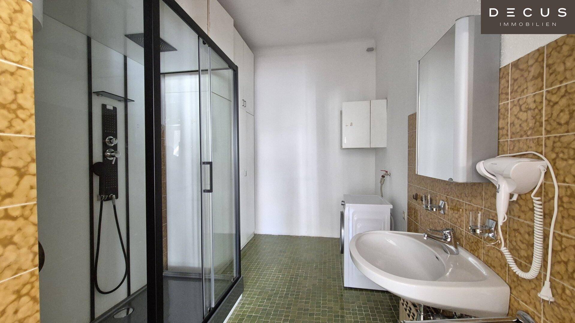 Badezimmer mit Duschkabine, Waschbecken und Waschmaschine, praktisch eingerichtet.