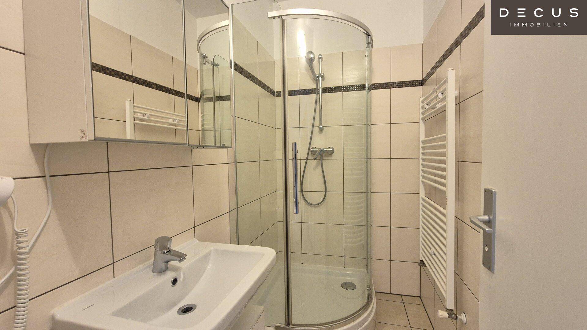 Badezimmer mit Duschkabine, Waschbecken, Spiegelschrank und beheiztem Handtuchhalter.