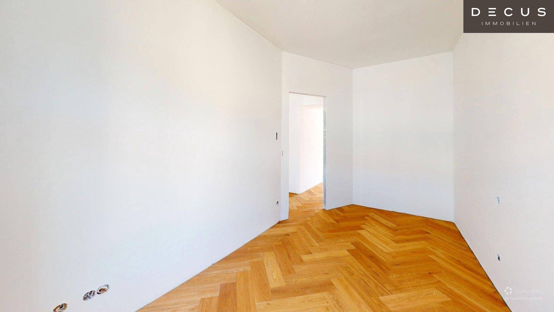 Leerer Raum mit Fischgrätparkett und offenem Durchgang zu einem weiteren Zimmer.