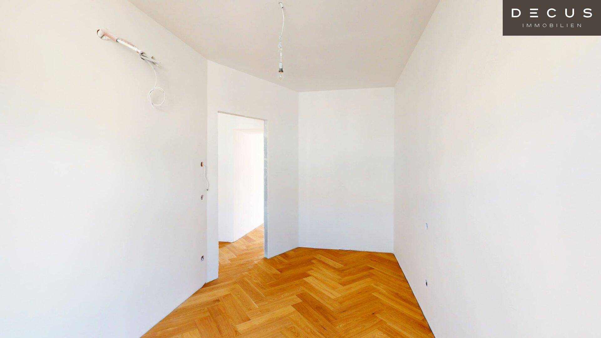 Leerer Raum mit Fischgrätparkett und offenem Durchgang, bereit für die weitere Gestaltung.