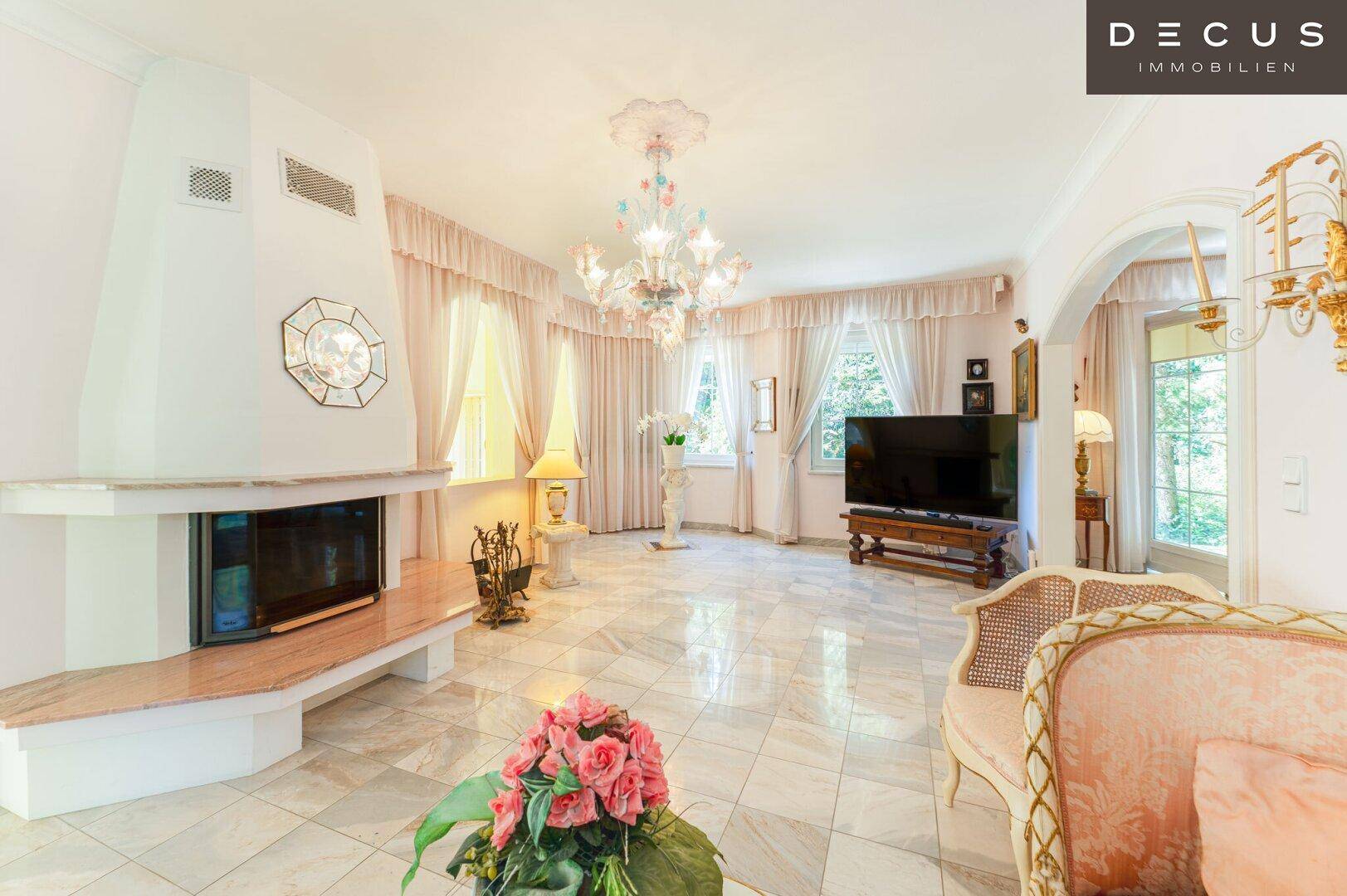 Klassisches Wohnzimmer mit Marmorboden, Kamin und opulentem Kronleuchter in Pastelltönen.
