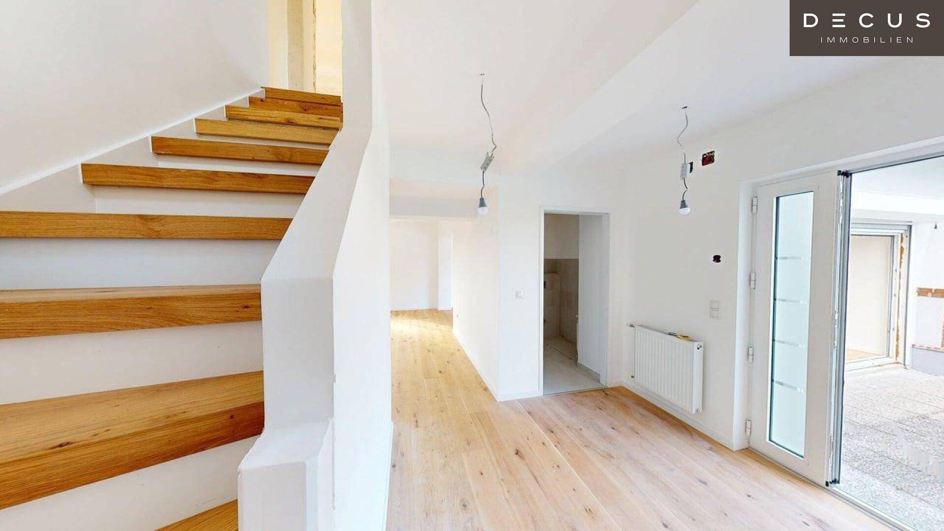 Heller Flur mit Holztreppe und Holzboden, der zu weiteren Räumen führt.