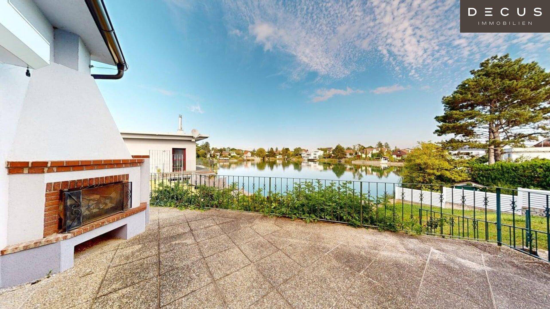 Geräumige Terrasse mit Außenkamin und Fliesenboden, ideal für entspannte Stunden am See.