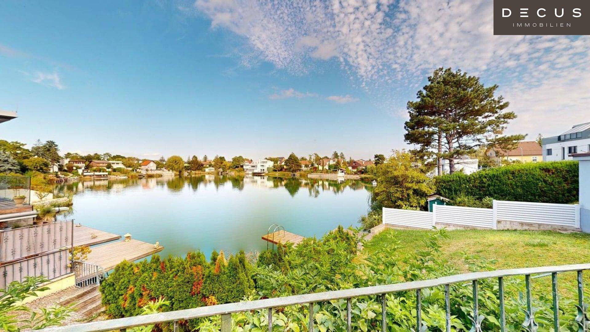 Malerischer Blick auf den See mit umliegenden Häusern und üppiger Vegetation am Ufer.