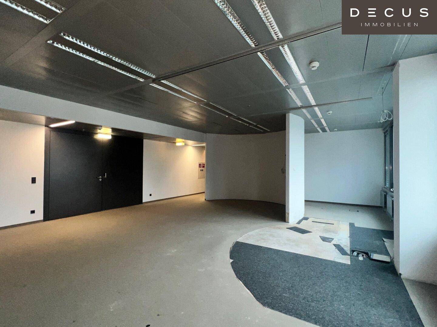 Großer, leerer Büroraum mit abgehängter Decke und teilweise entferntem Bodenbelag, bereit für den Ausbau.